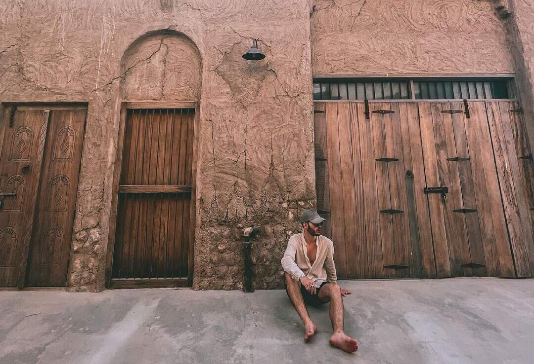 Male traveller sitting in front of doorways in ancient city