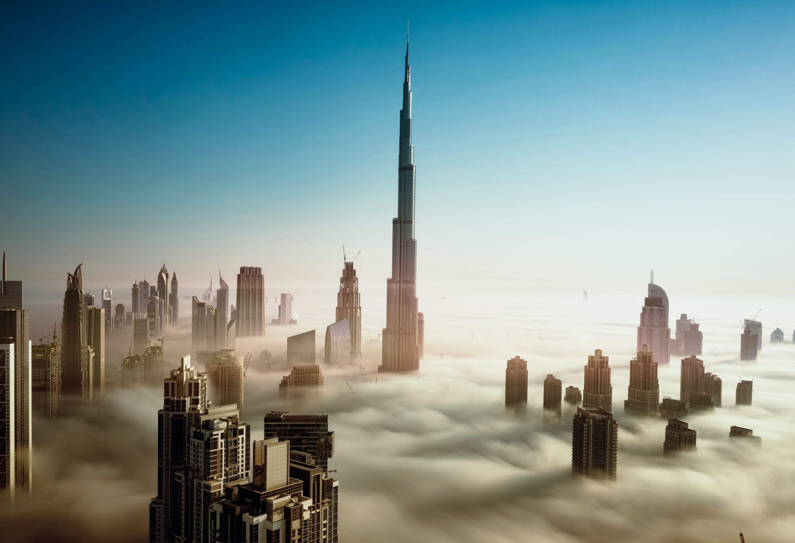 Dubai's skyline is dominated by modern skyscrapers, including the world's tallest building, the Burj Khalifa, in the early morning fog.
