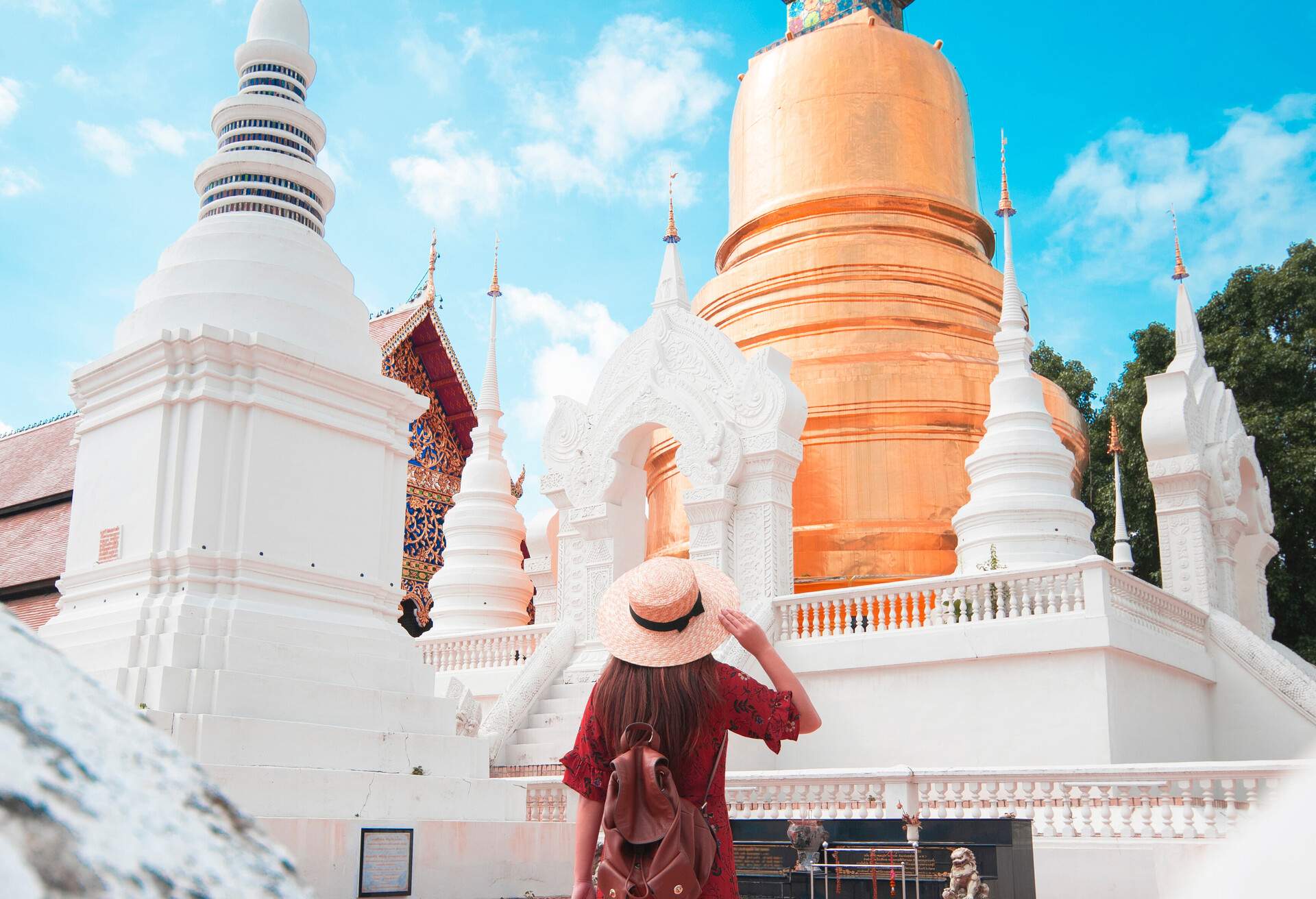 A lady tourist looks in awe at the golden royal temple with a bell-shaped chedi surrounded by white pagodas.