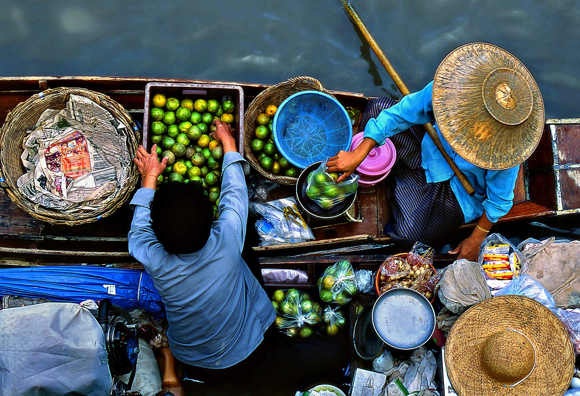 Two vendors selling fruits on a floating market.