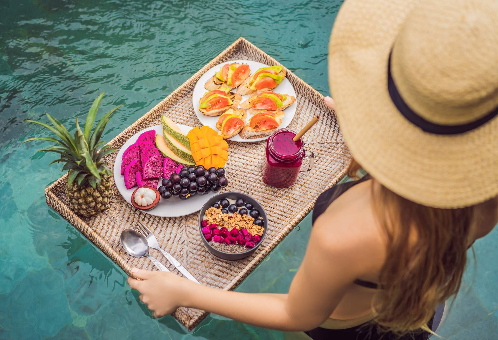 A woman holding a food tray loaded with fruits as she goes into the swimming pool.