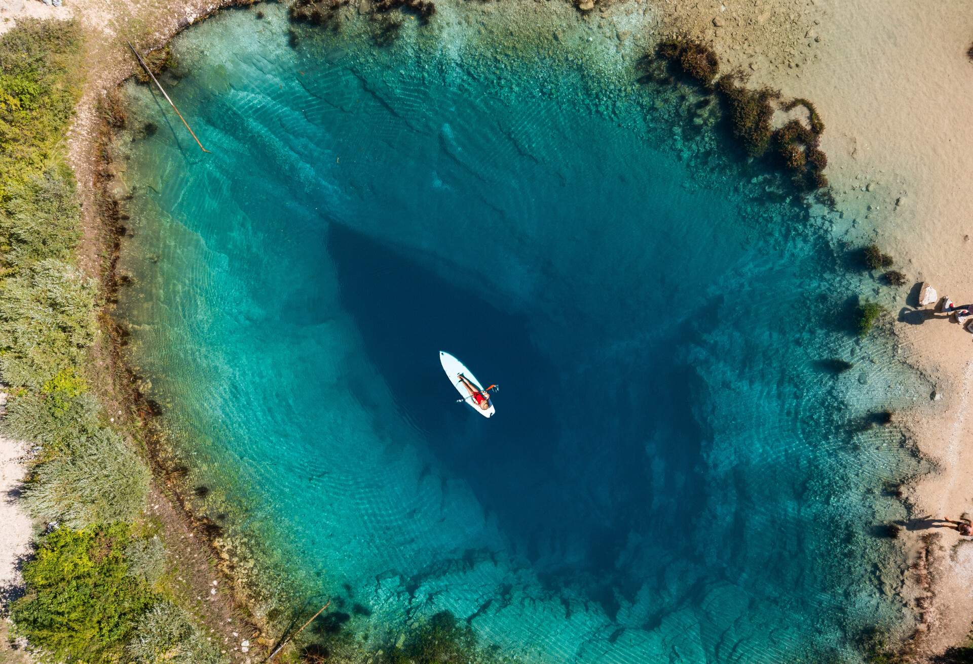 Woman on a stand-up paddle board floating in an azure natural lake 