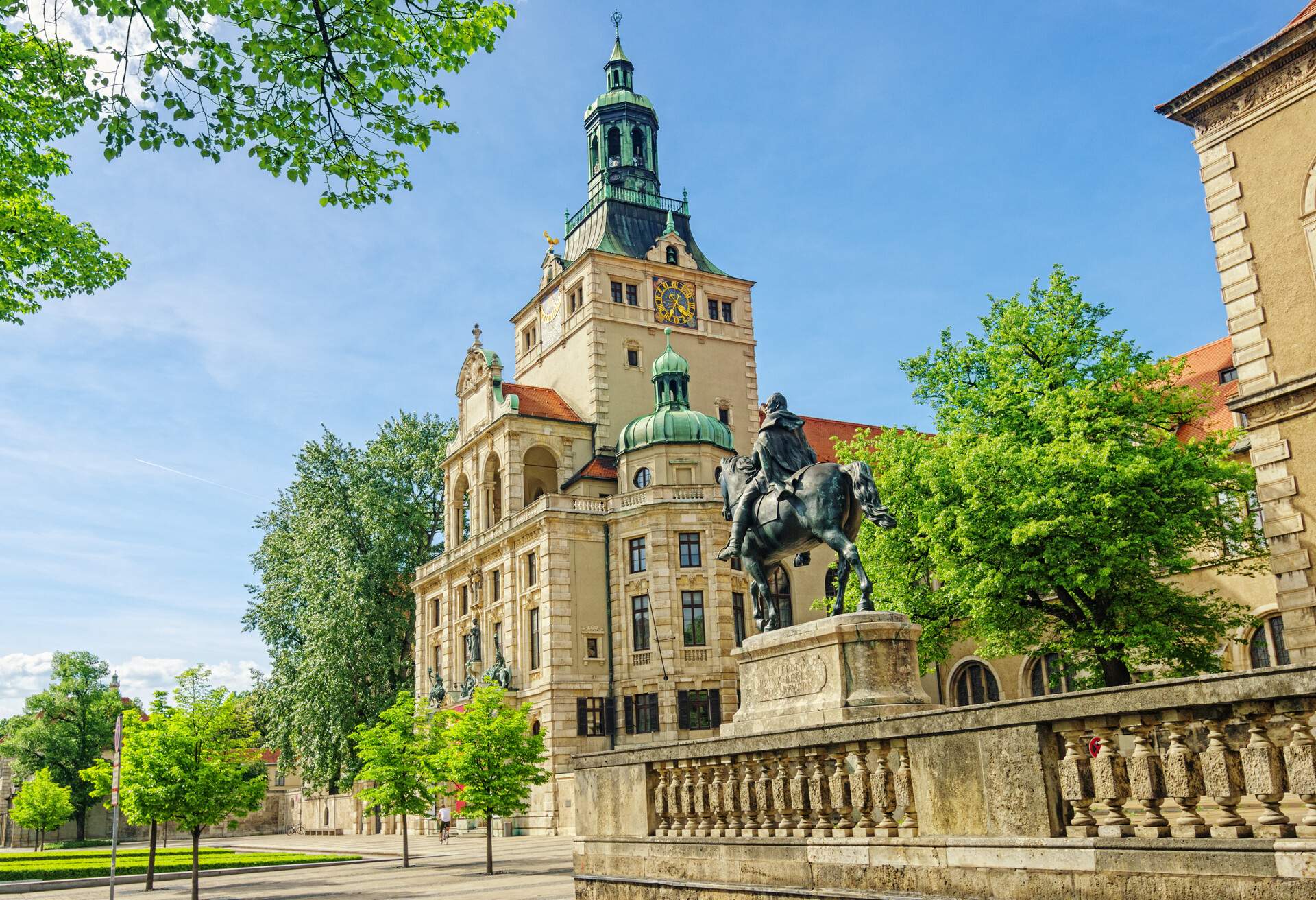 An equestrian statue topped on a pedestal adjacent to an enormous museum building.