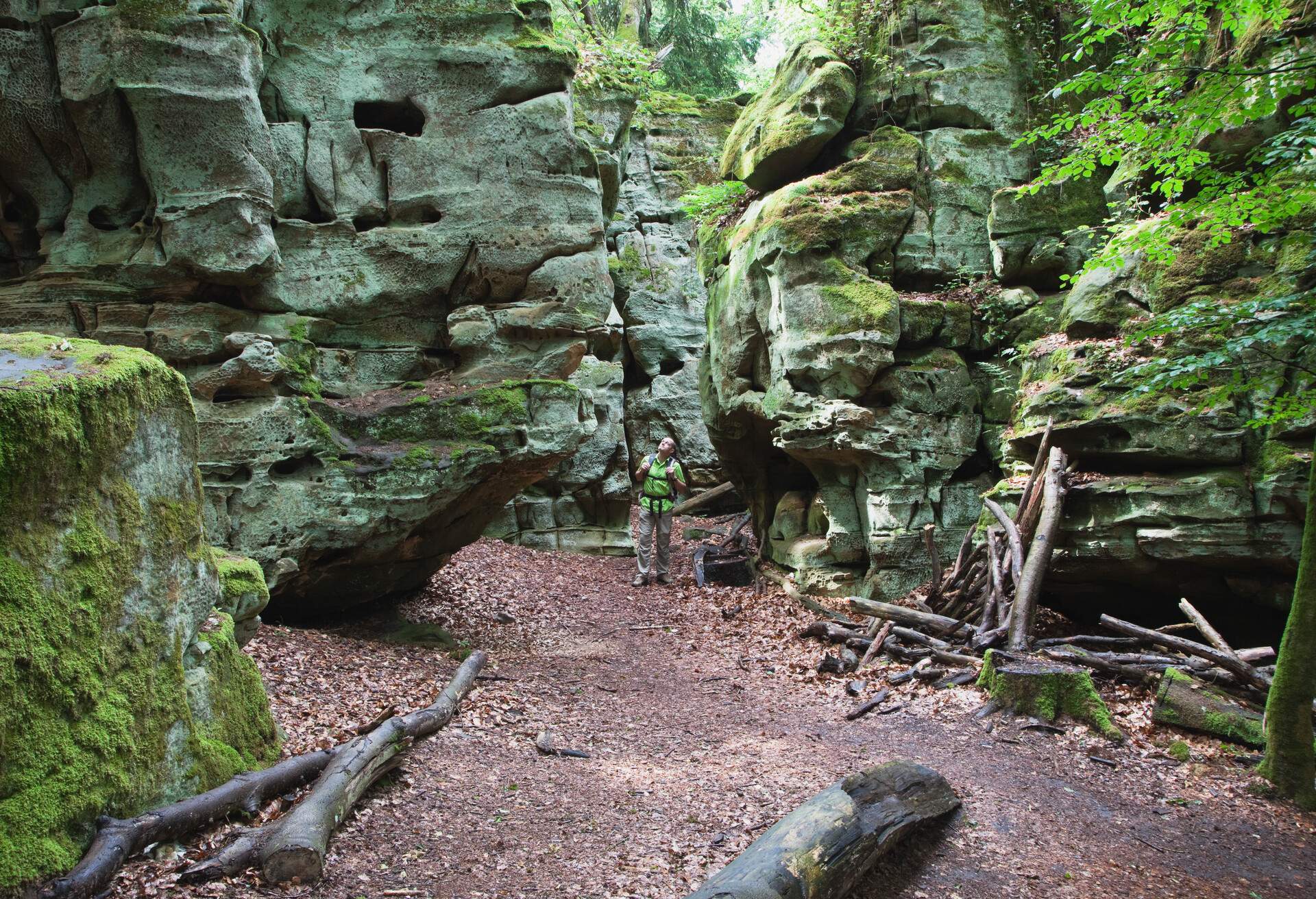 A man standing in the fissure of towering rock formations.