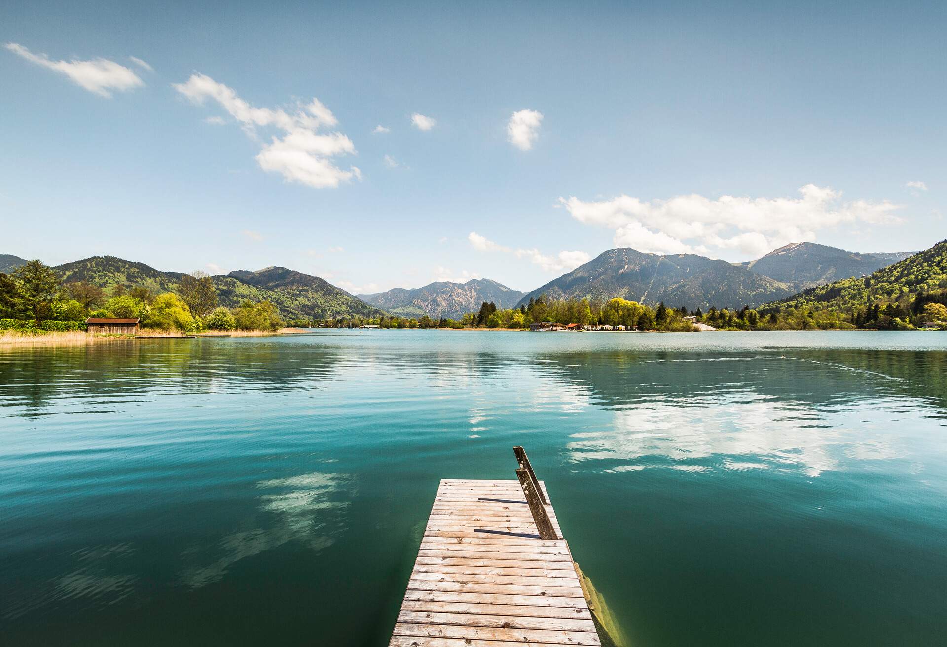 Wooden pier with a ladder on a peaceful lake surrounded by fall foliage.