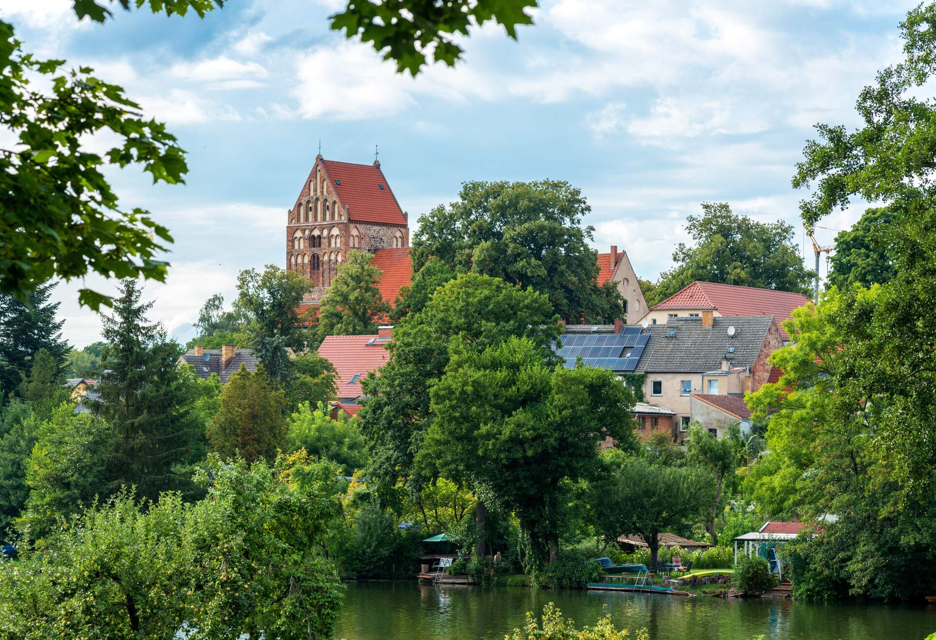Village houses and a church hidden behind the trees along the shores of a lake.