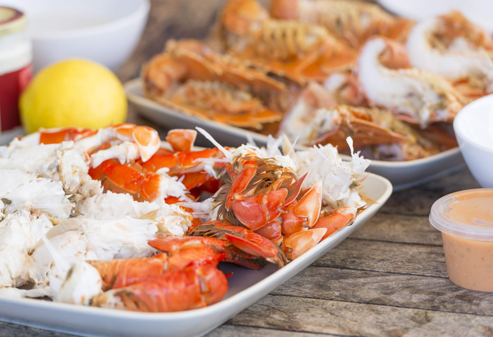 A platter of crab meat with its shells on a wooden table.