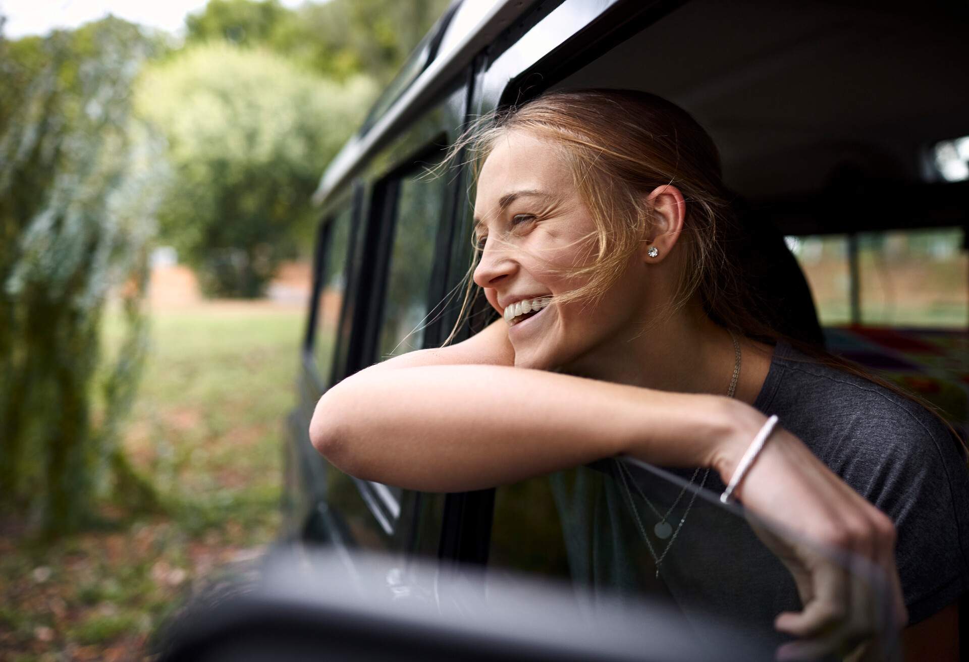 Smiling woman in a car looking outside the window