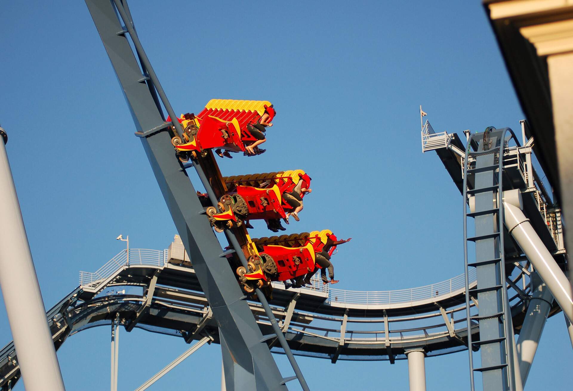 A roller coaster car hurtling downward at high speed, with the riders' feet exhilaratingly flying out in front of them.