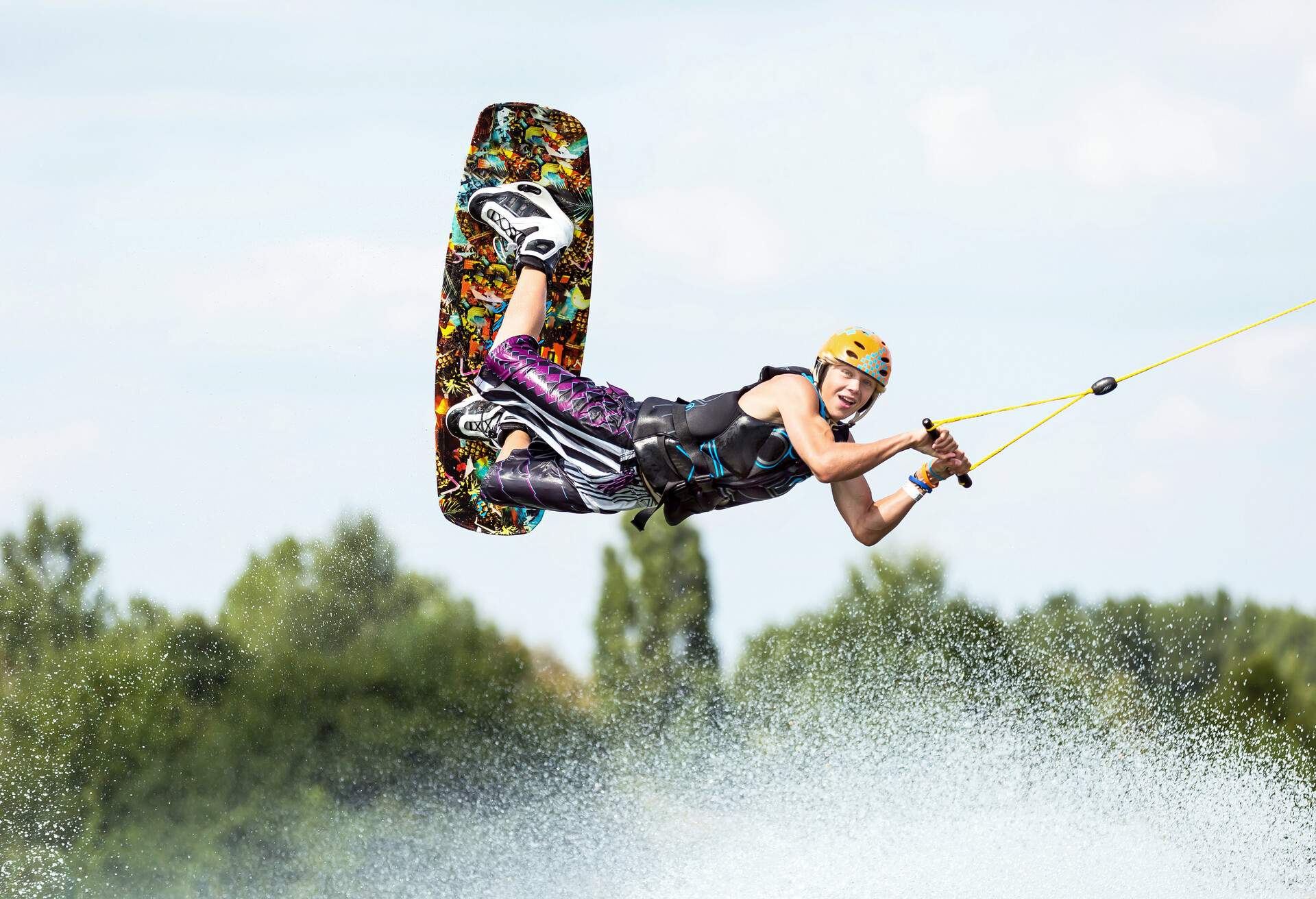 Young wakeboarder flying over the splashing waterdrops