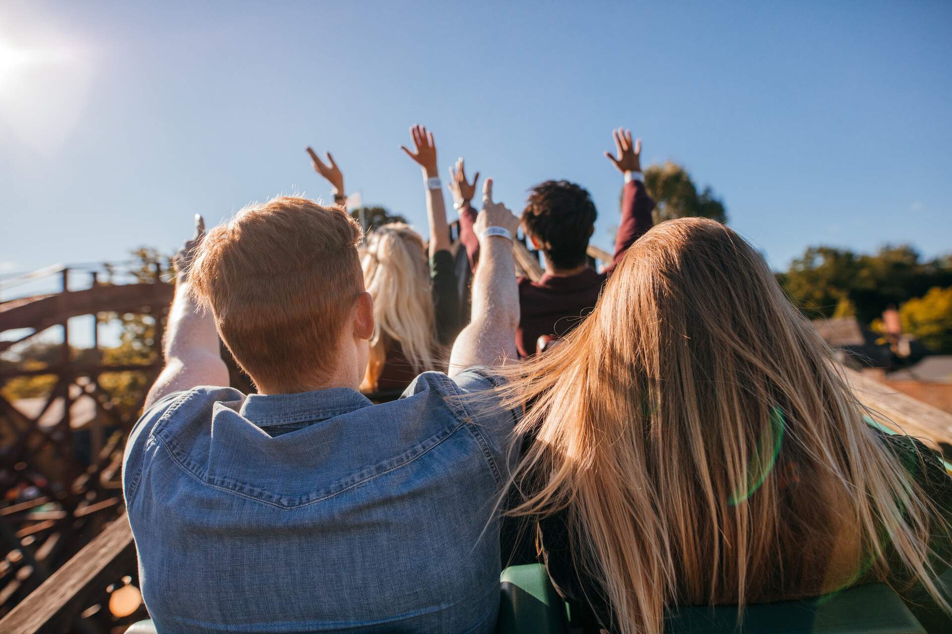 People on a roller coaster ride raise their hands.