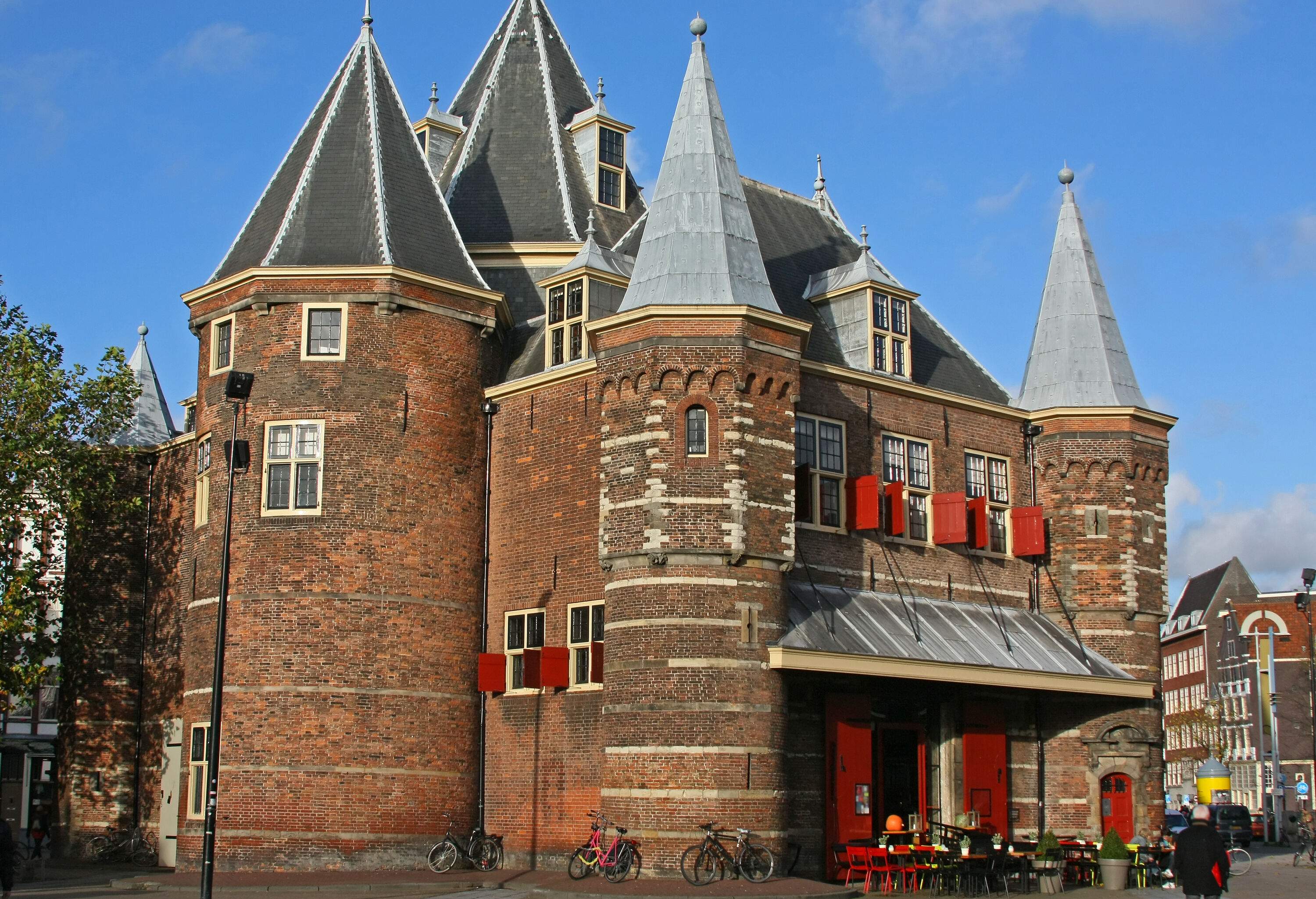 A castle-like structure with conical-shaped tower roofs in a public square.