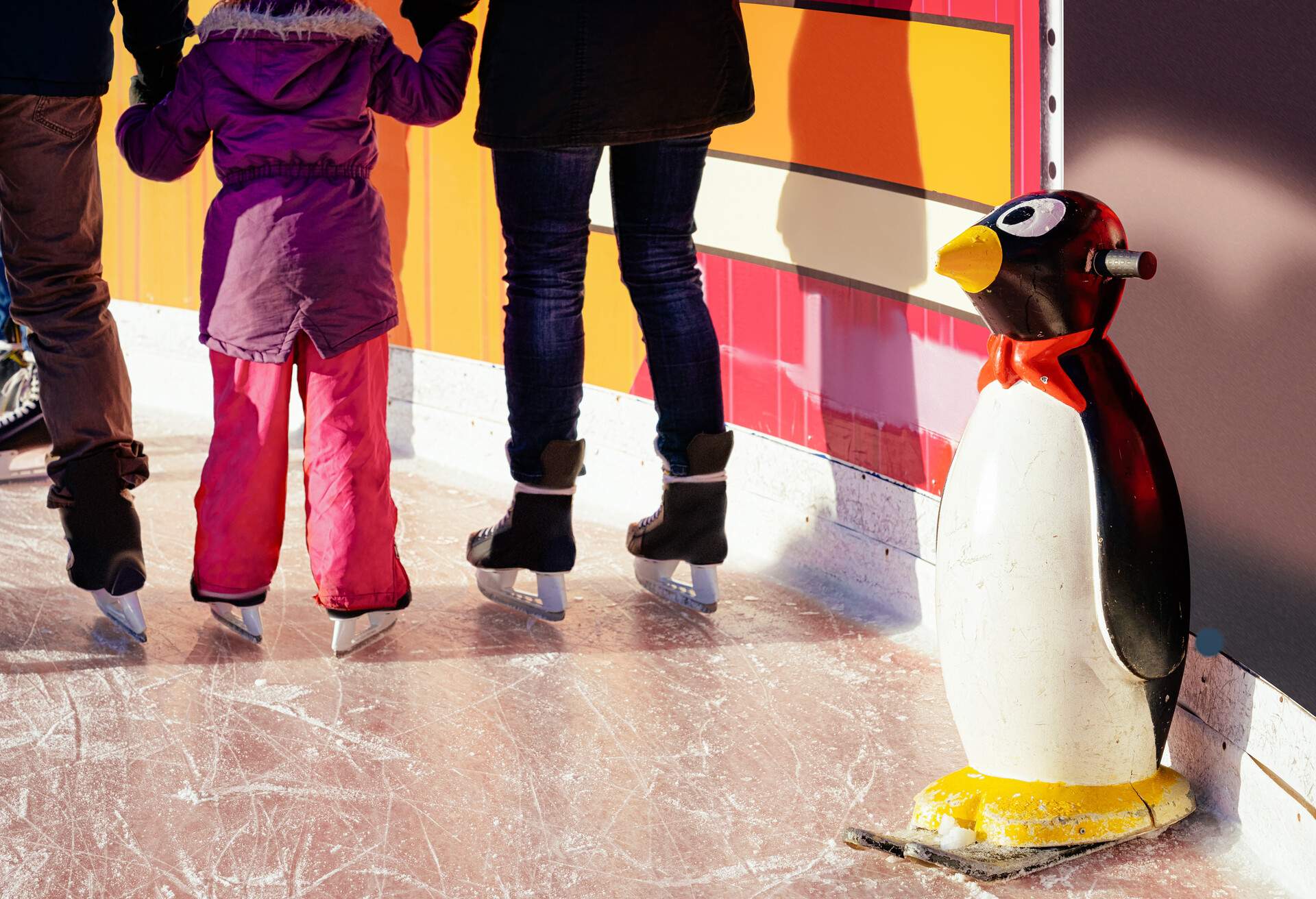 Penguin skate aids and assistant and family doing skating on the winter rink at Christmas market in Berlin in Germany in Europe in winter. Holiday day out with skates.
