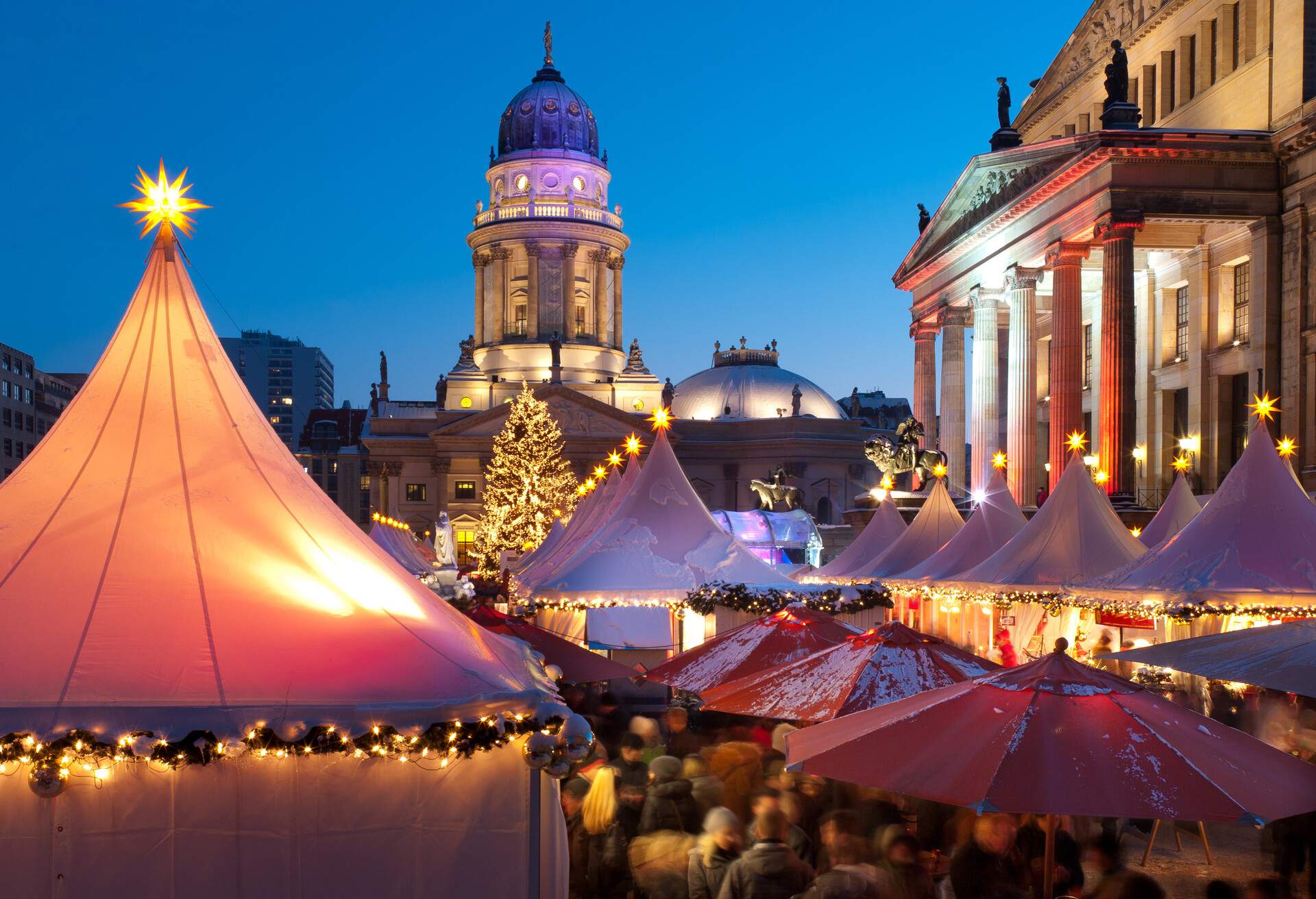 A church tower overlooking the Christmas market shops with star-topped white pagoda tents.