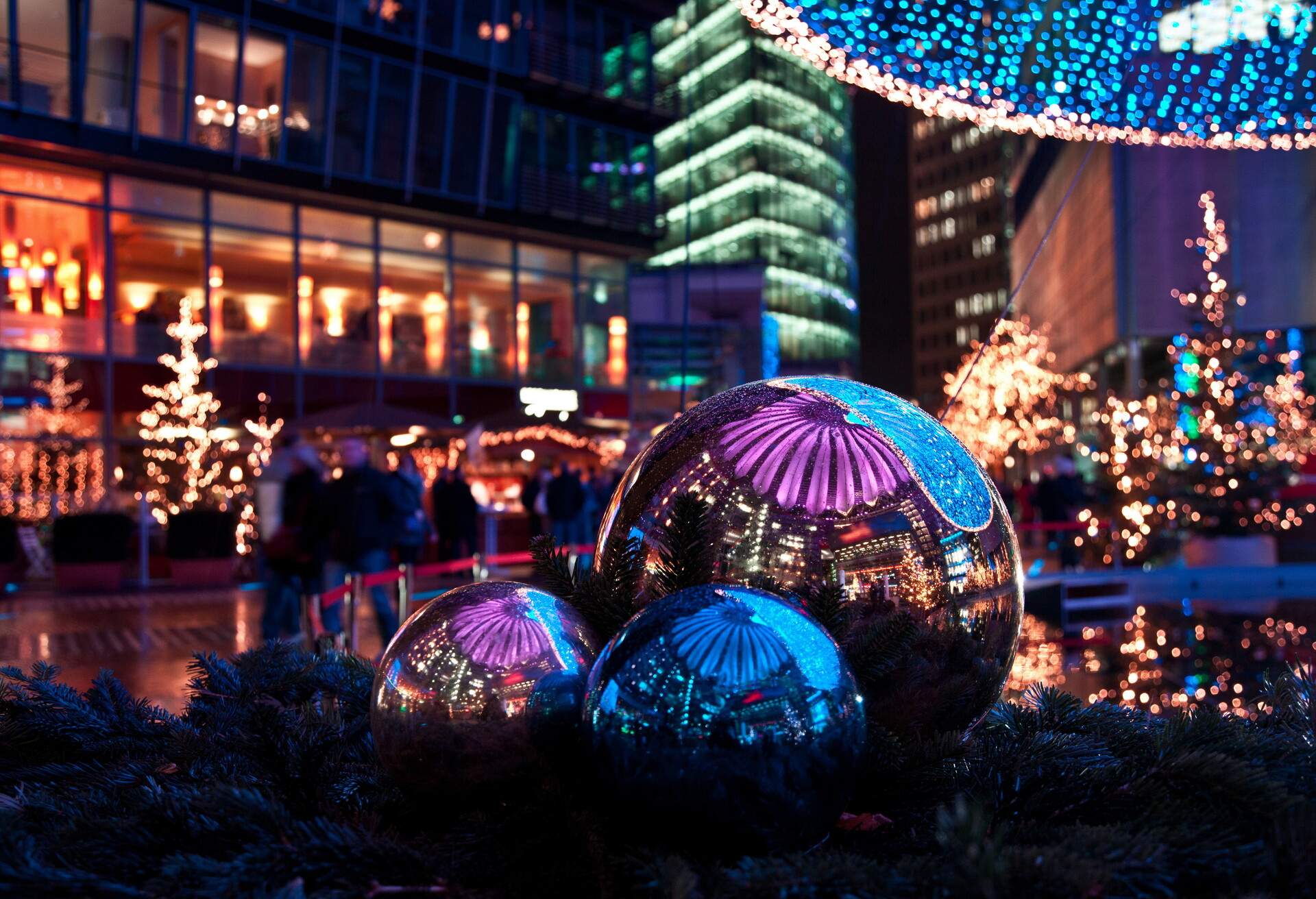 The beautiful night of the christmas market decorated with lights in the Sony Center of Berlin, you can see the whole christmas market in the metal balls.