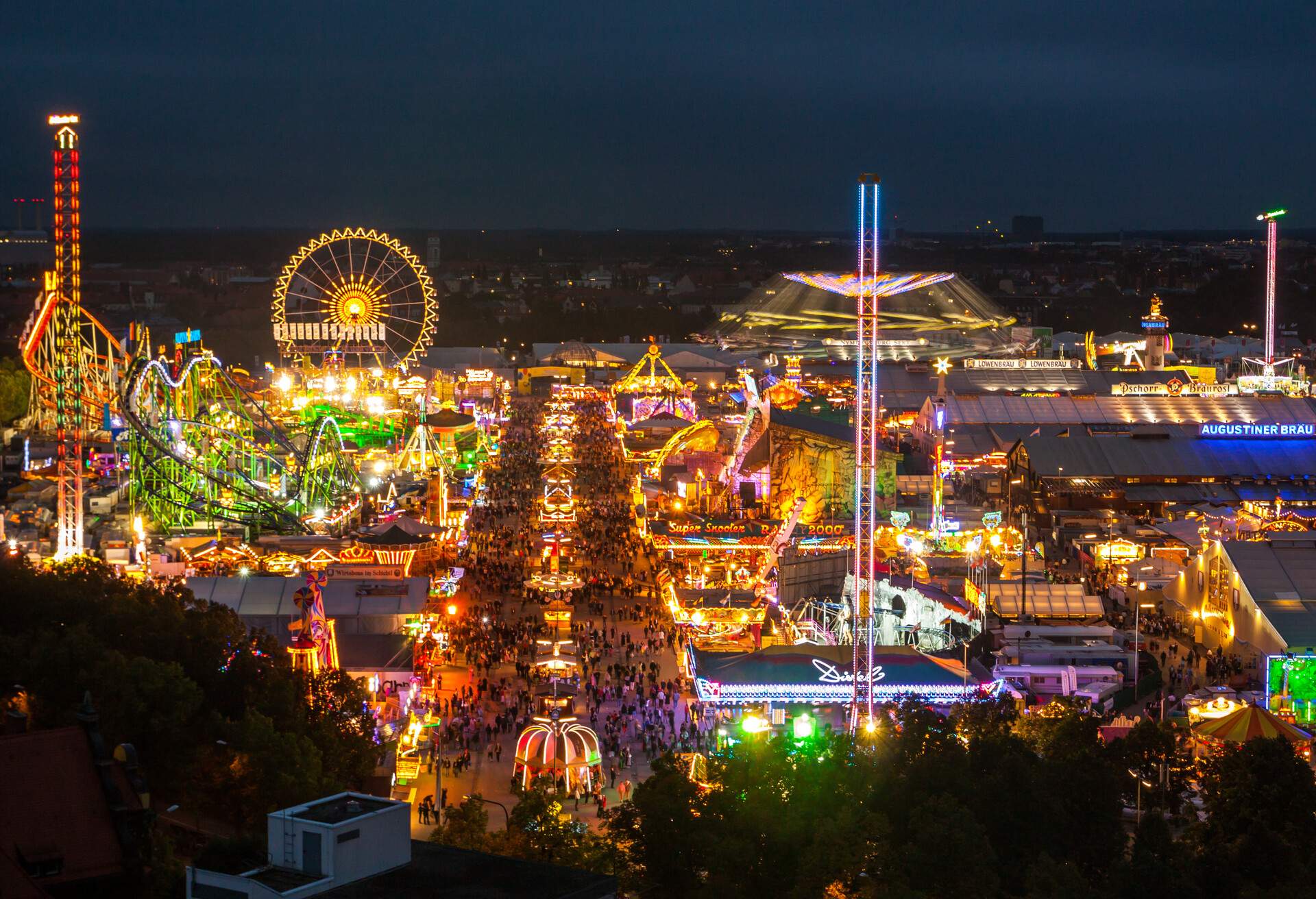 A crowded, brightly illuminated amusement park under the dark night sky.