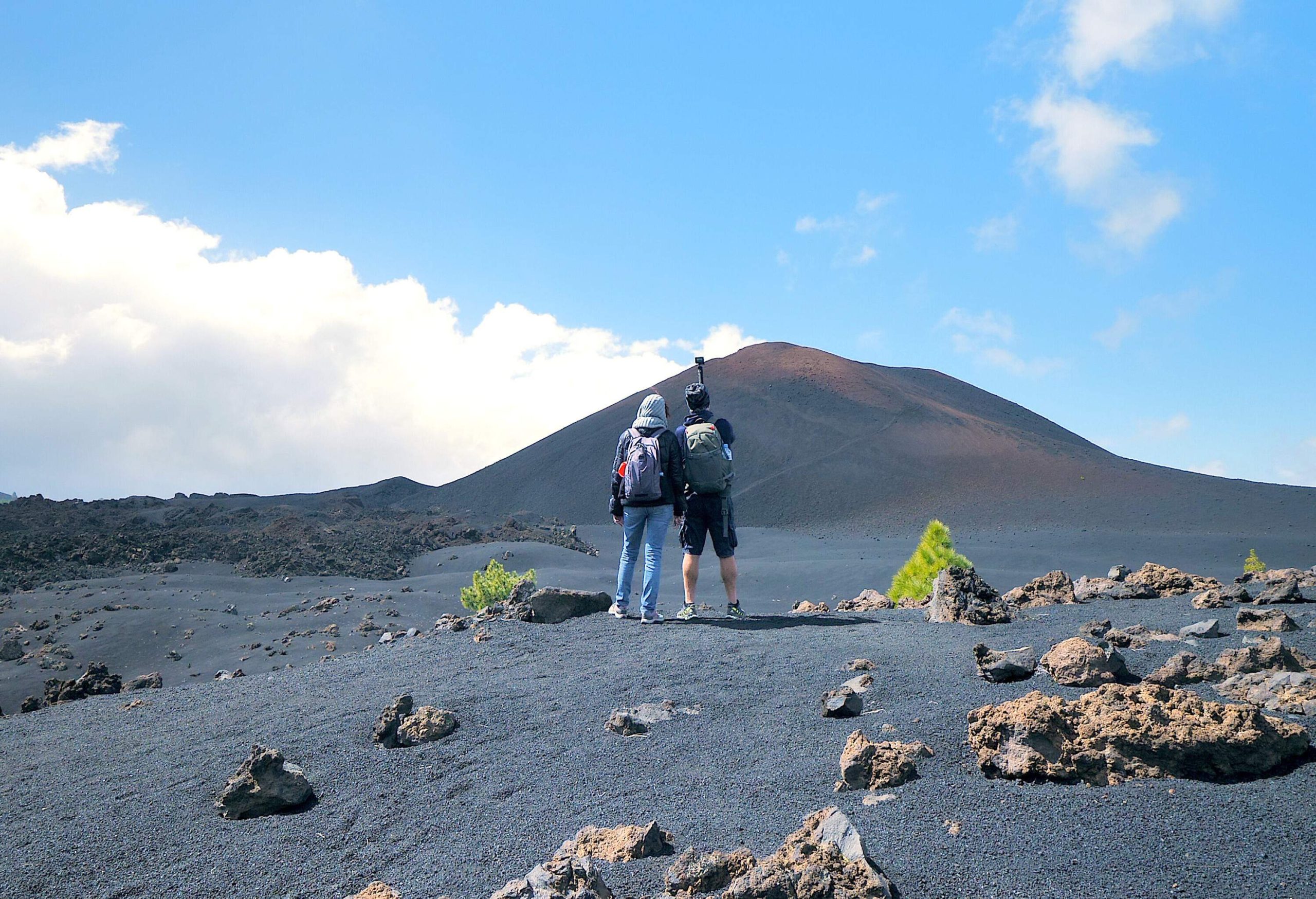 A couple with an action camera taking a photo of a volcano.