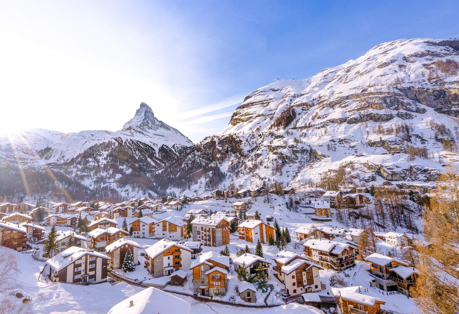 A charming snow-covered town nestled in the heart of a breathtaking landscape, embraced by towering rocky mountains.