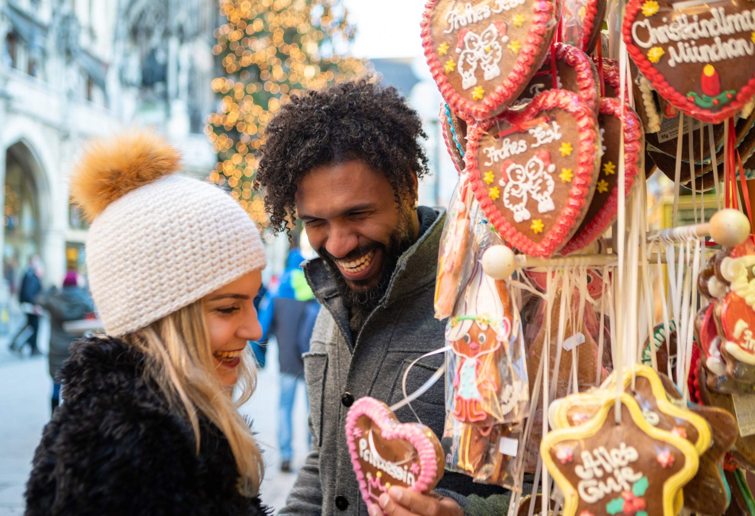 A couple smiling while looking at a piece of a heart-shaped Christmas souvenir.