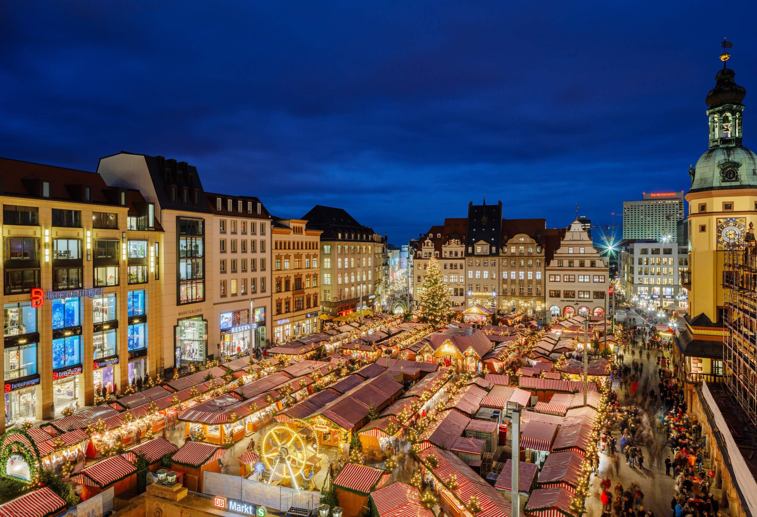 A market filled with holiday-decorated stores and bordered by structures.