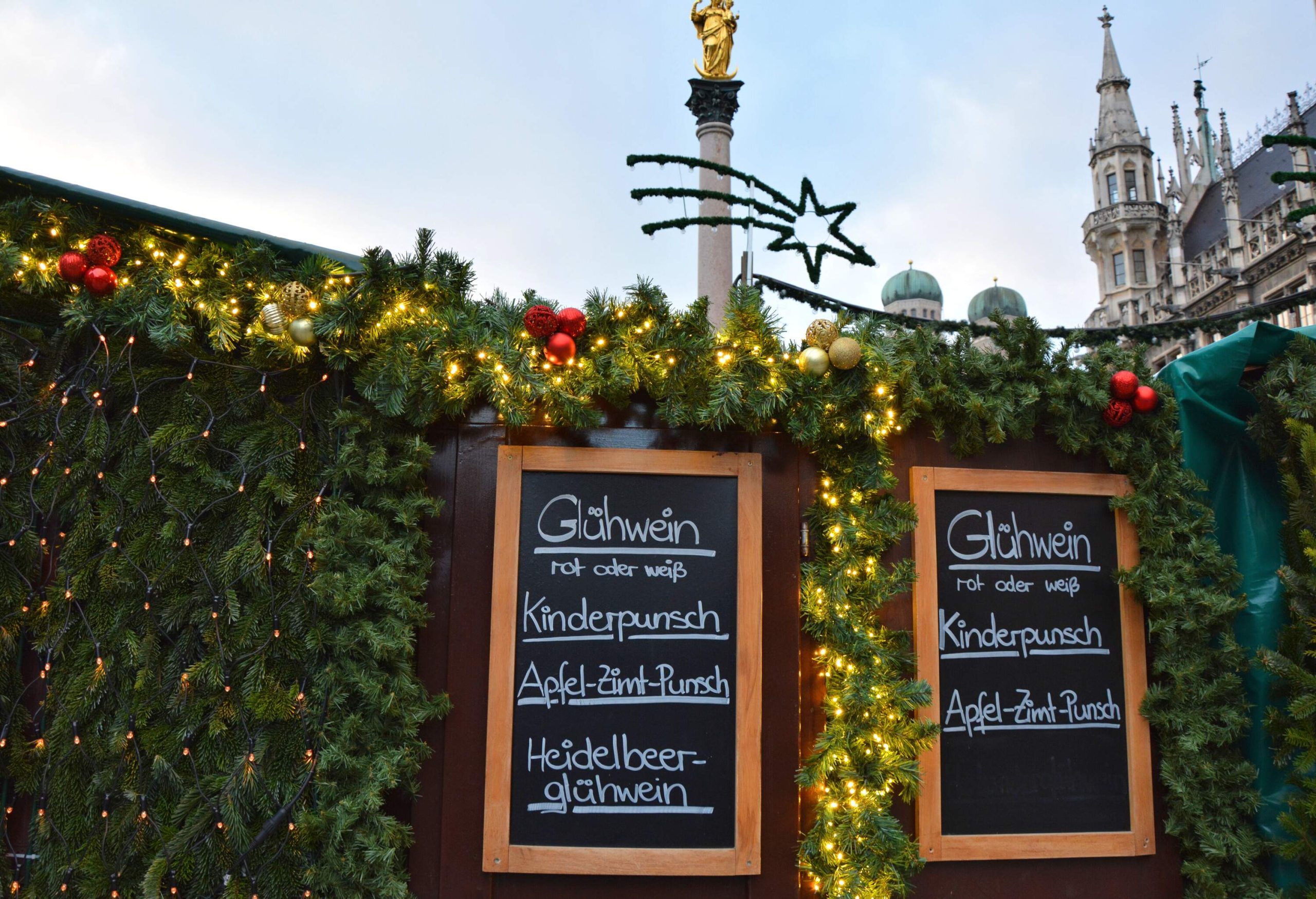 A handwritten drinks menu in German language, written on the menu board on the wall decorated with Christmas ornaments.