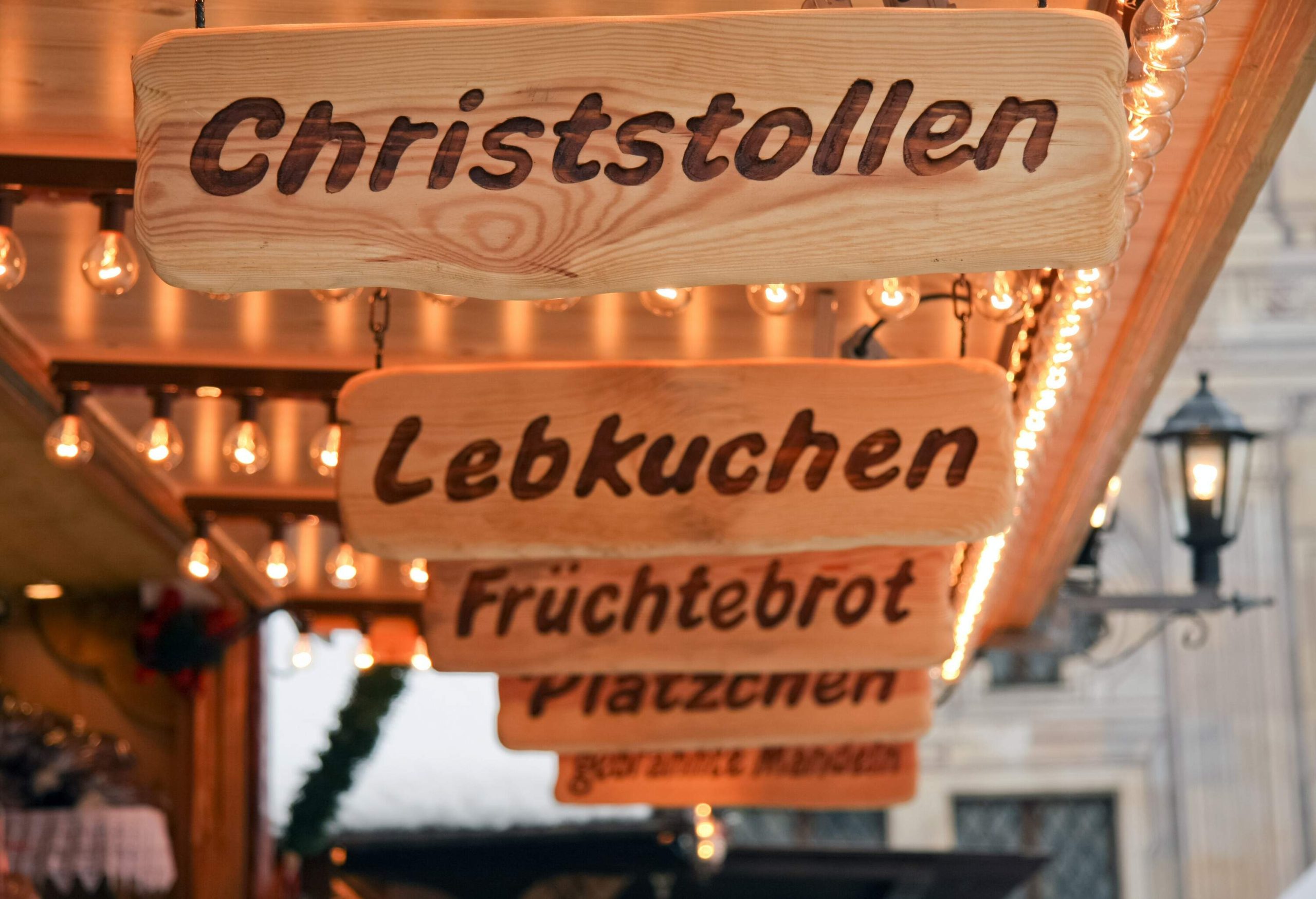 Wood burnt signs in the German language, illuminated with rows of light bulbs.