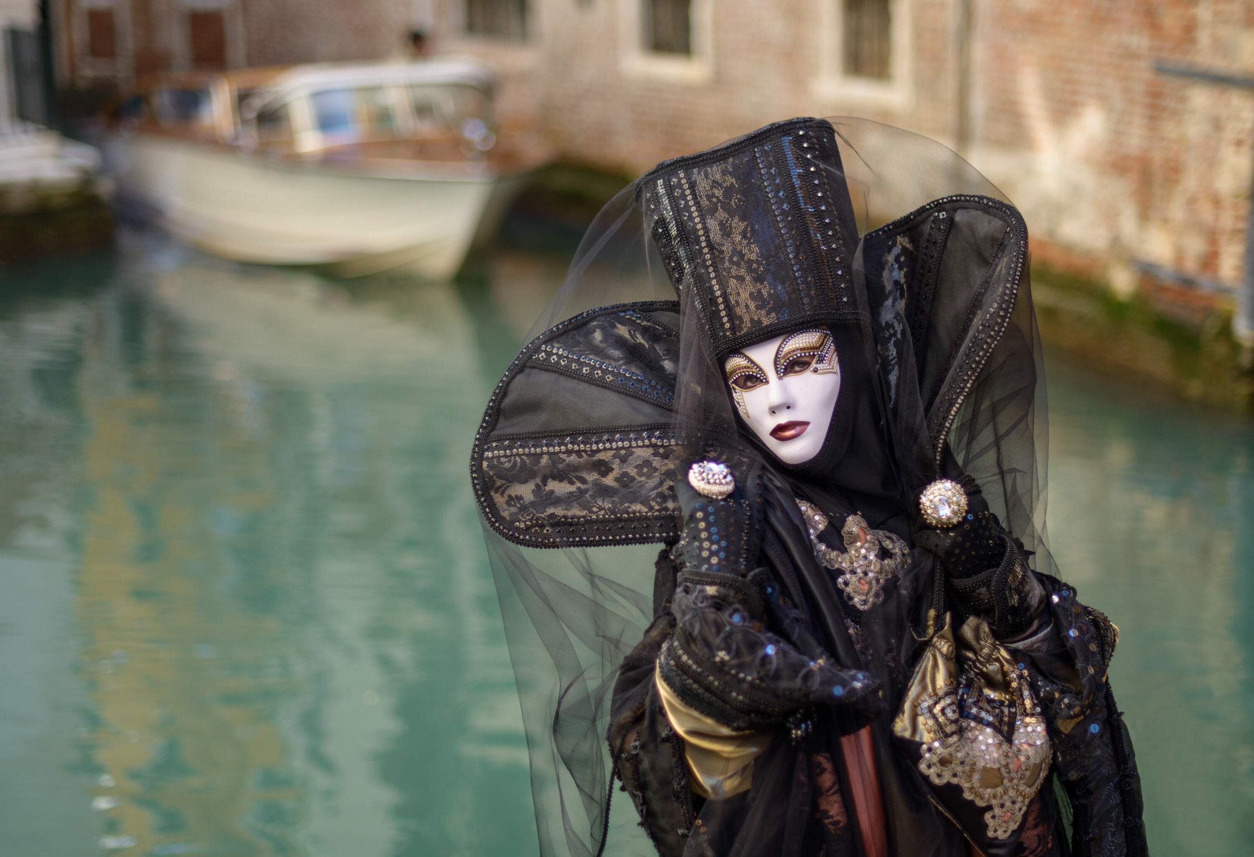 A person wearing a black festival costume with white carnival mask.