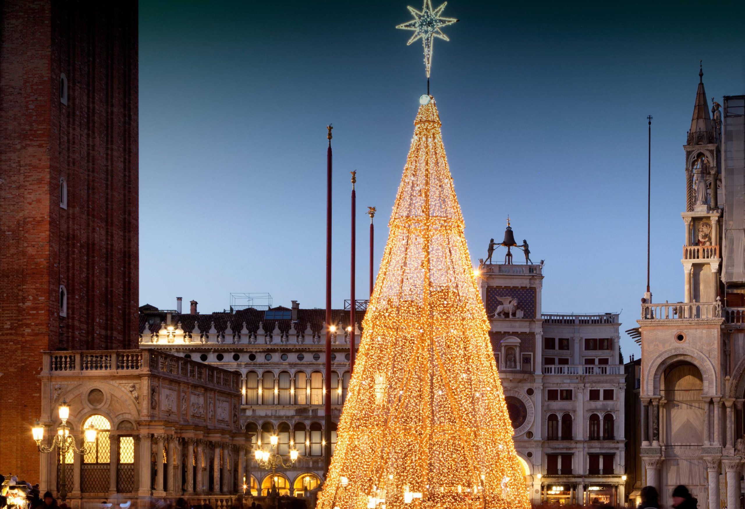 Renaissance-styled buildings surround a huge Christmas tree covered in yellow string lights.