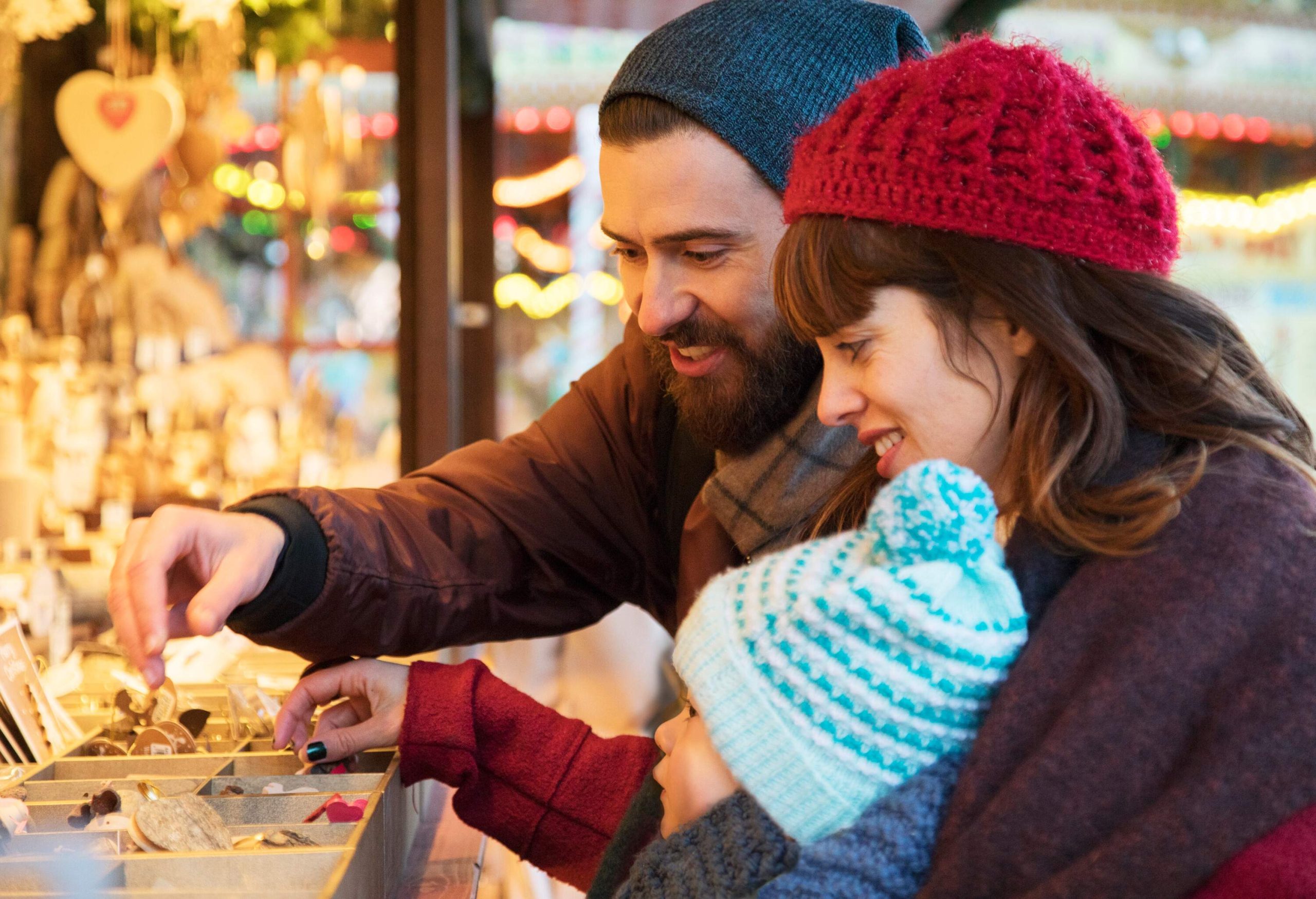 Happy family with small child shopping for trinkets at Christmas Market