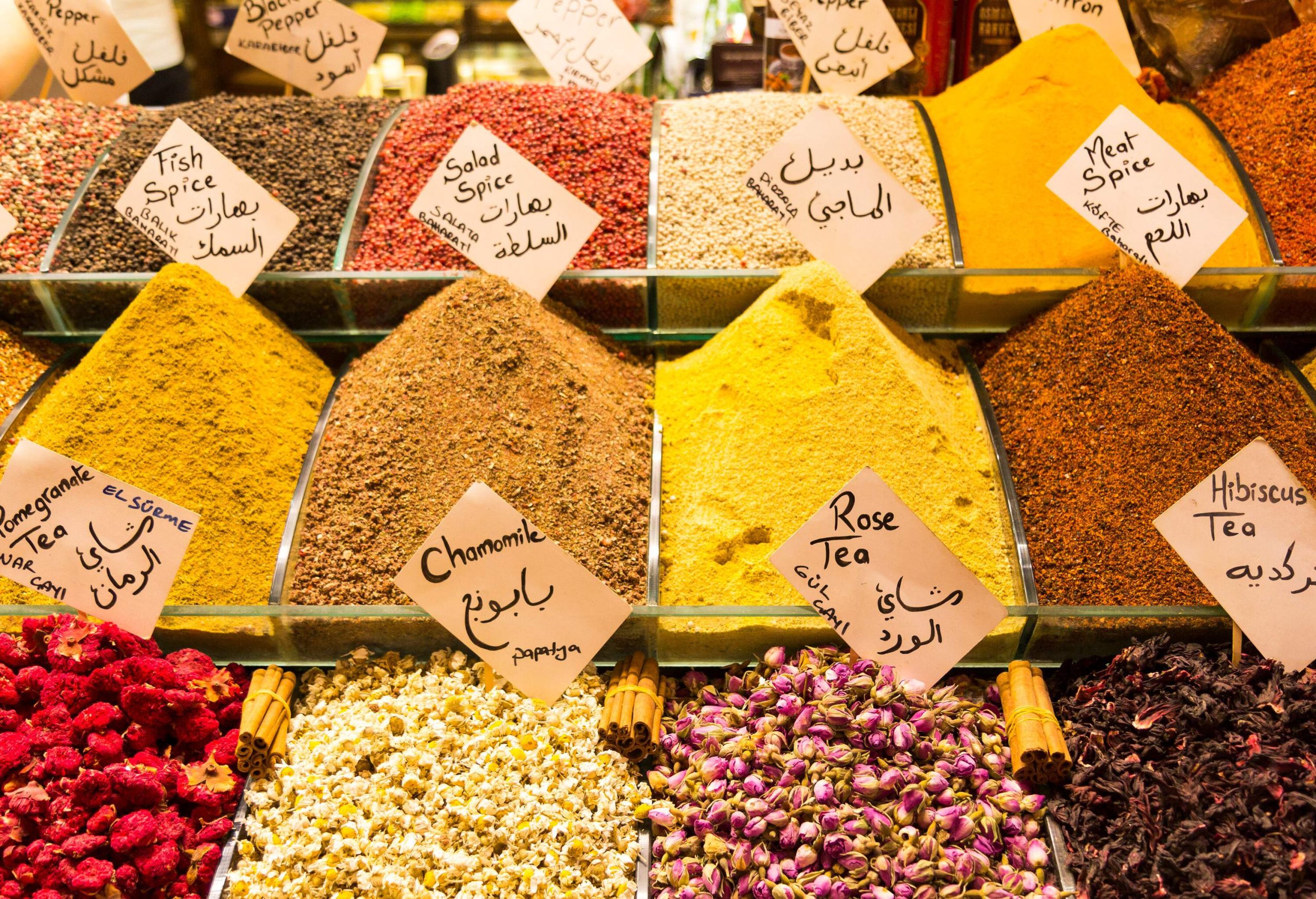 Mounds of colourful ground spices in glass containers on display.