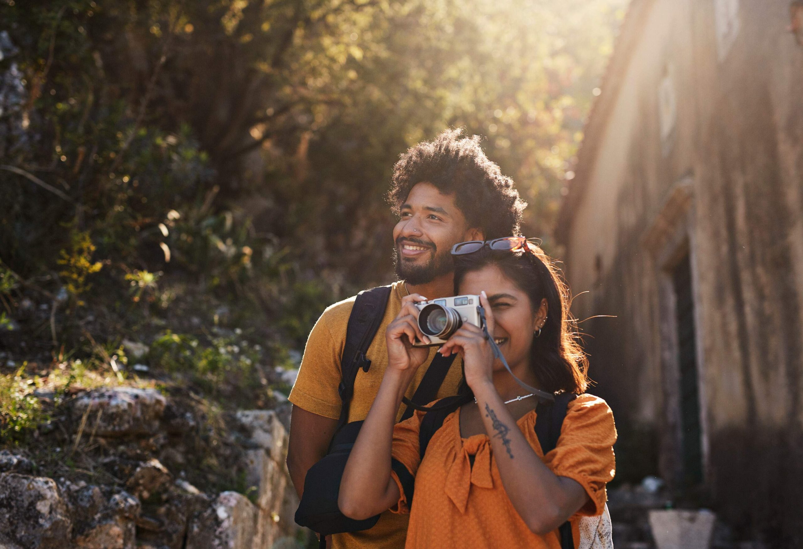 Young woman photographing through camera by boyfriend on sunny day during vacation