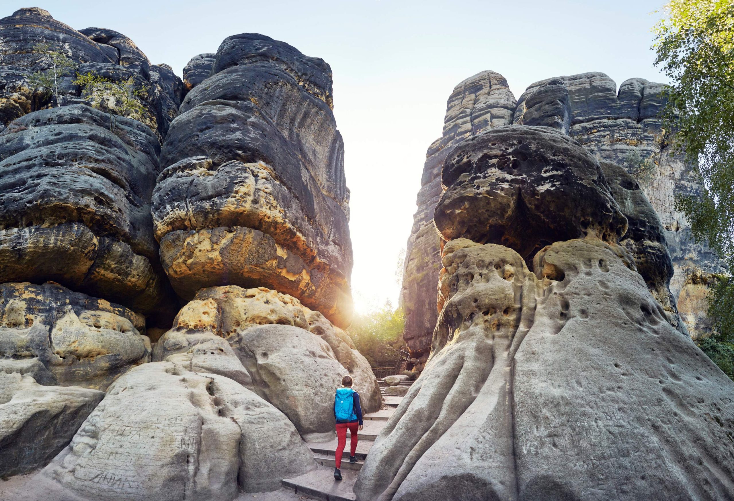 A woman climbing up the stairs between massive rock formations.