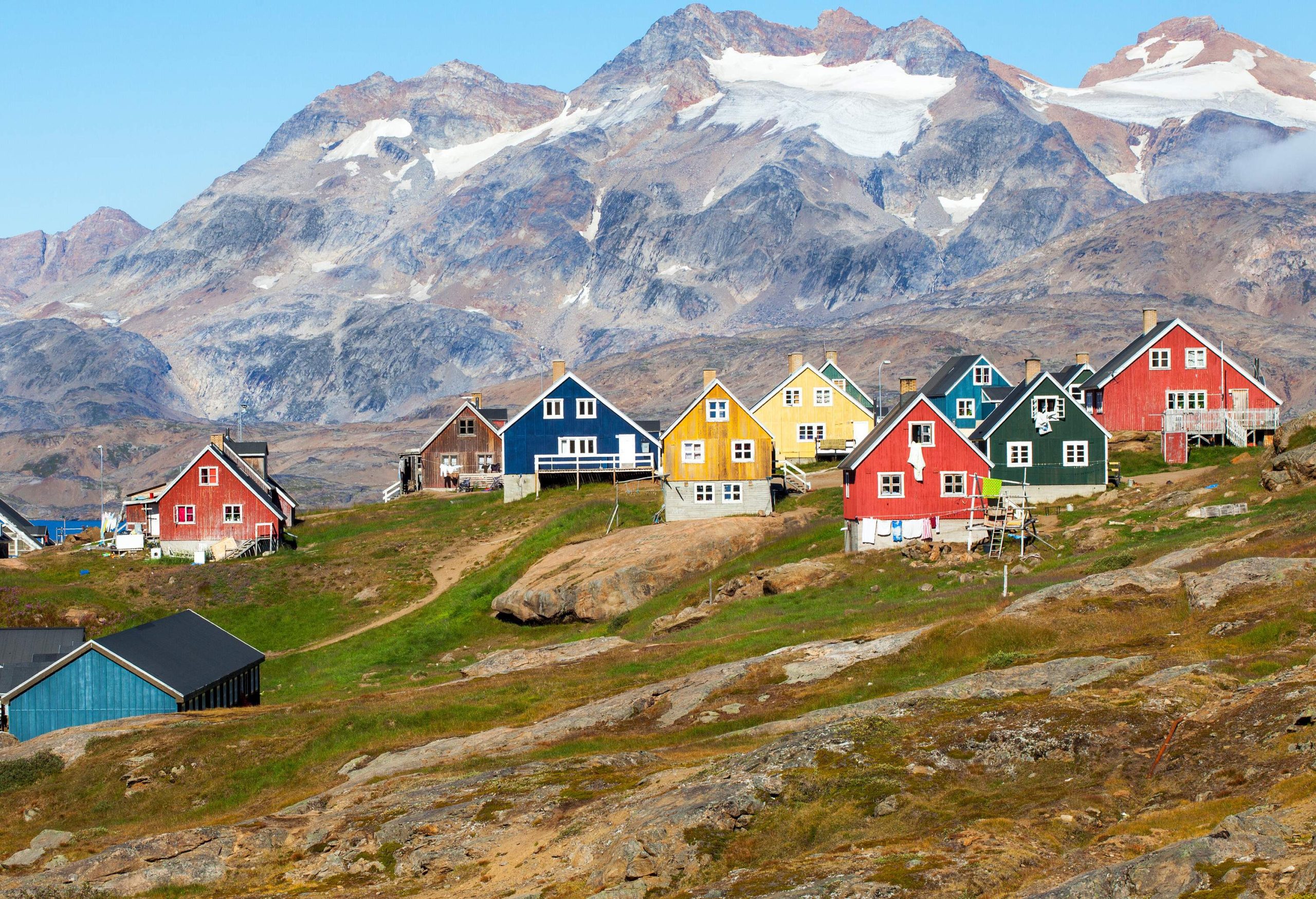 A scenic view of colourful houses slopes against the steep stone mountains.