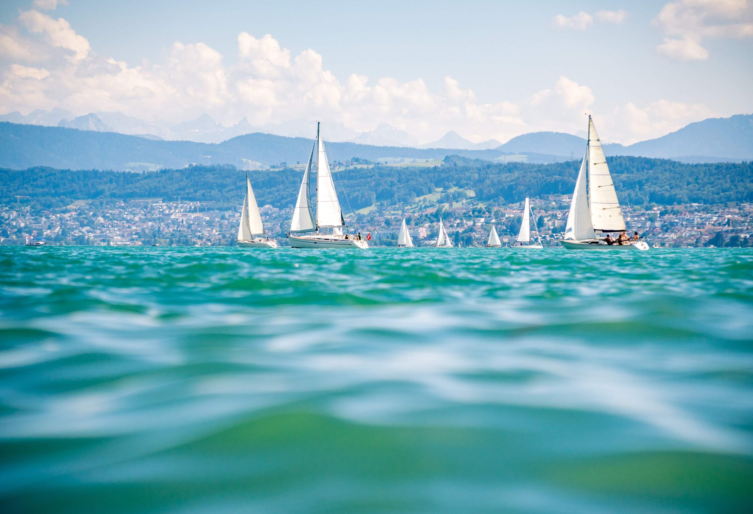 A fleet of sailing boats cruising on a lake.