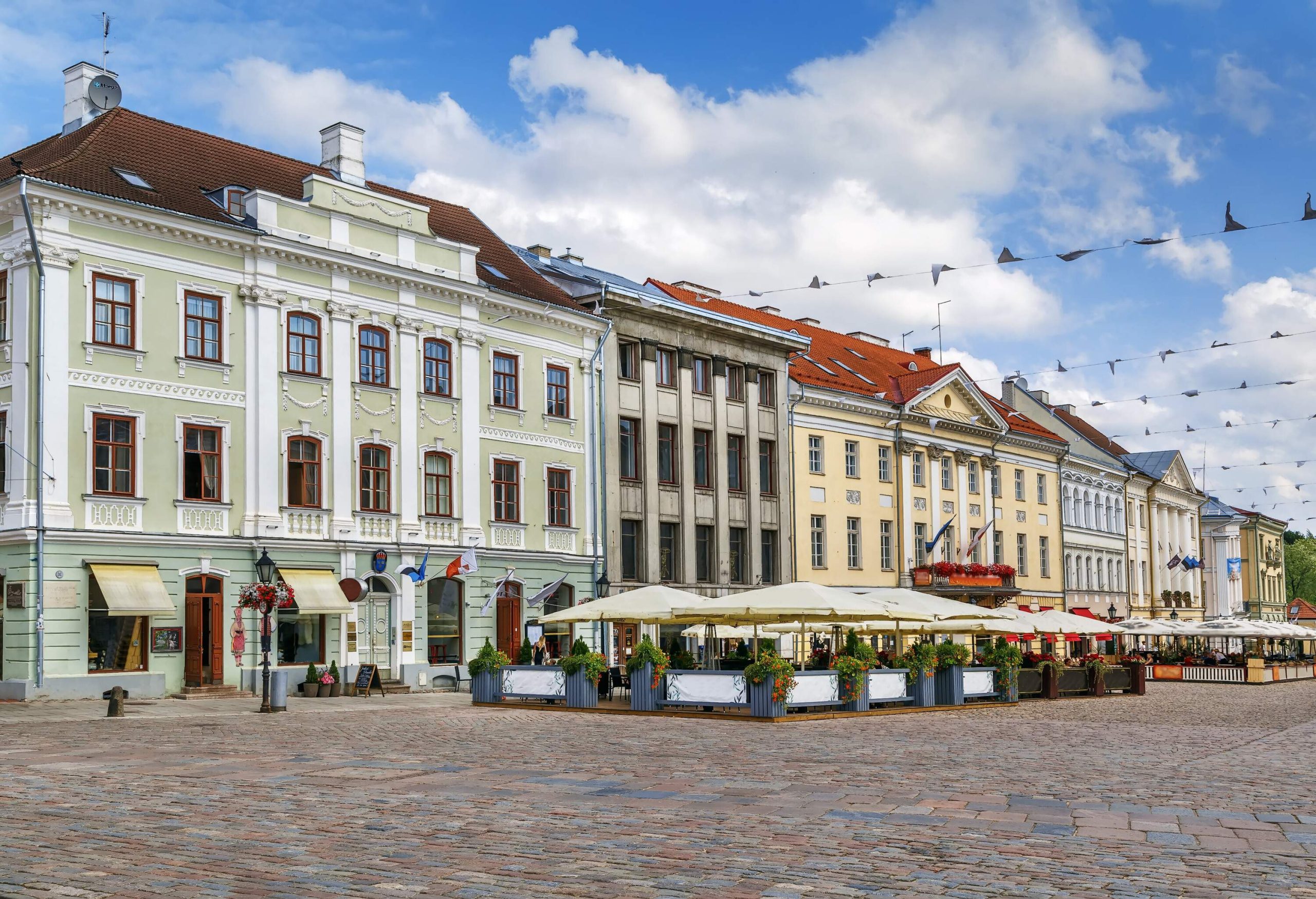 A public square with outdoor dining spots in tents along the adjacent city buildings.