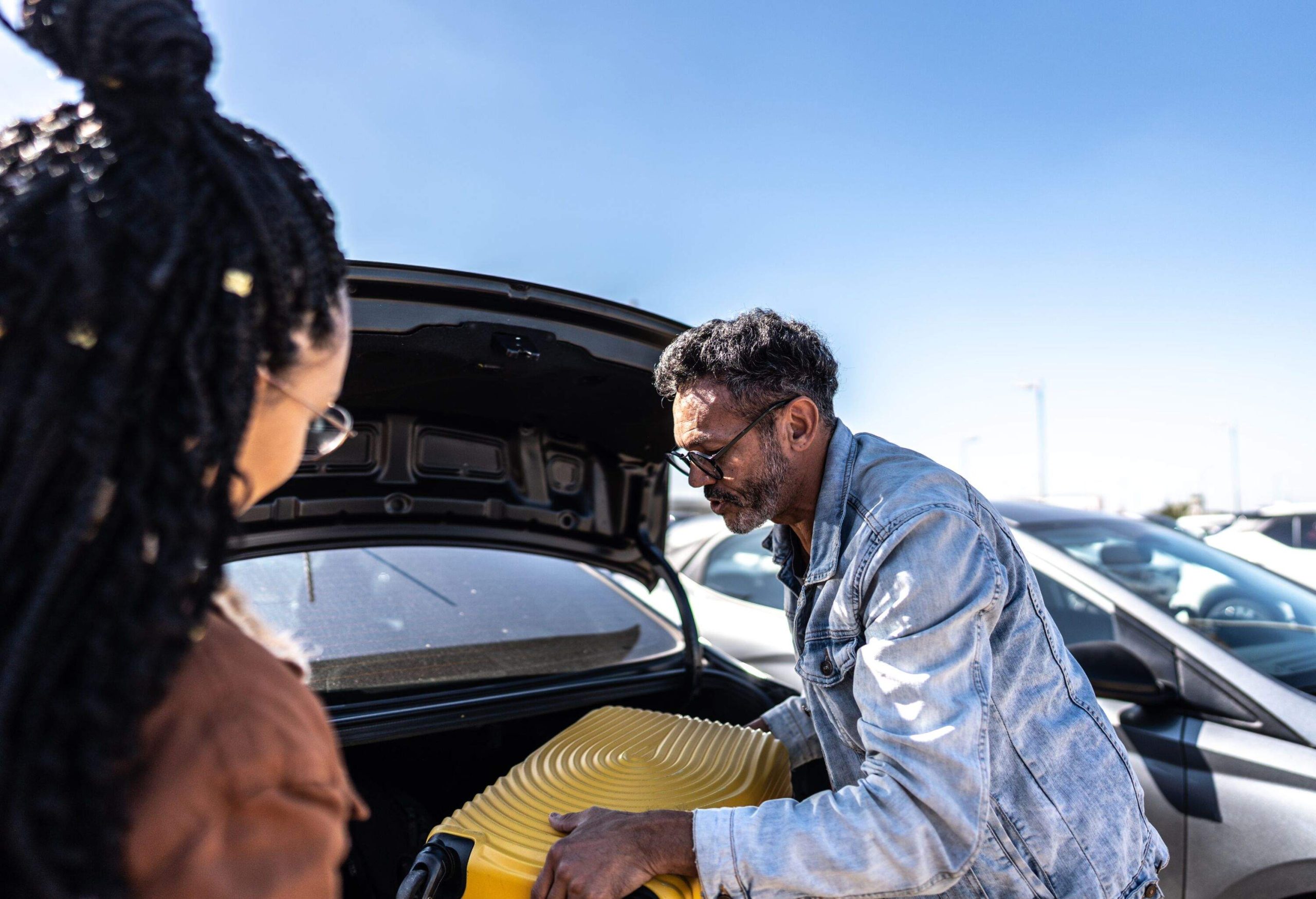 Friends picking luggage from the car trunk in parking lot at the airport