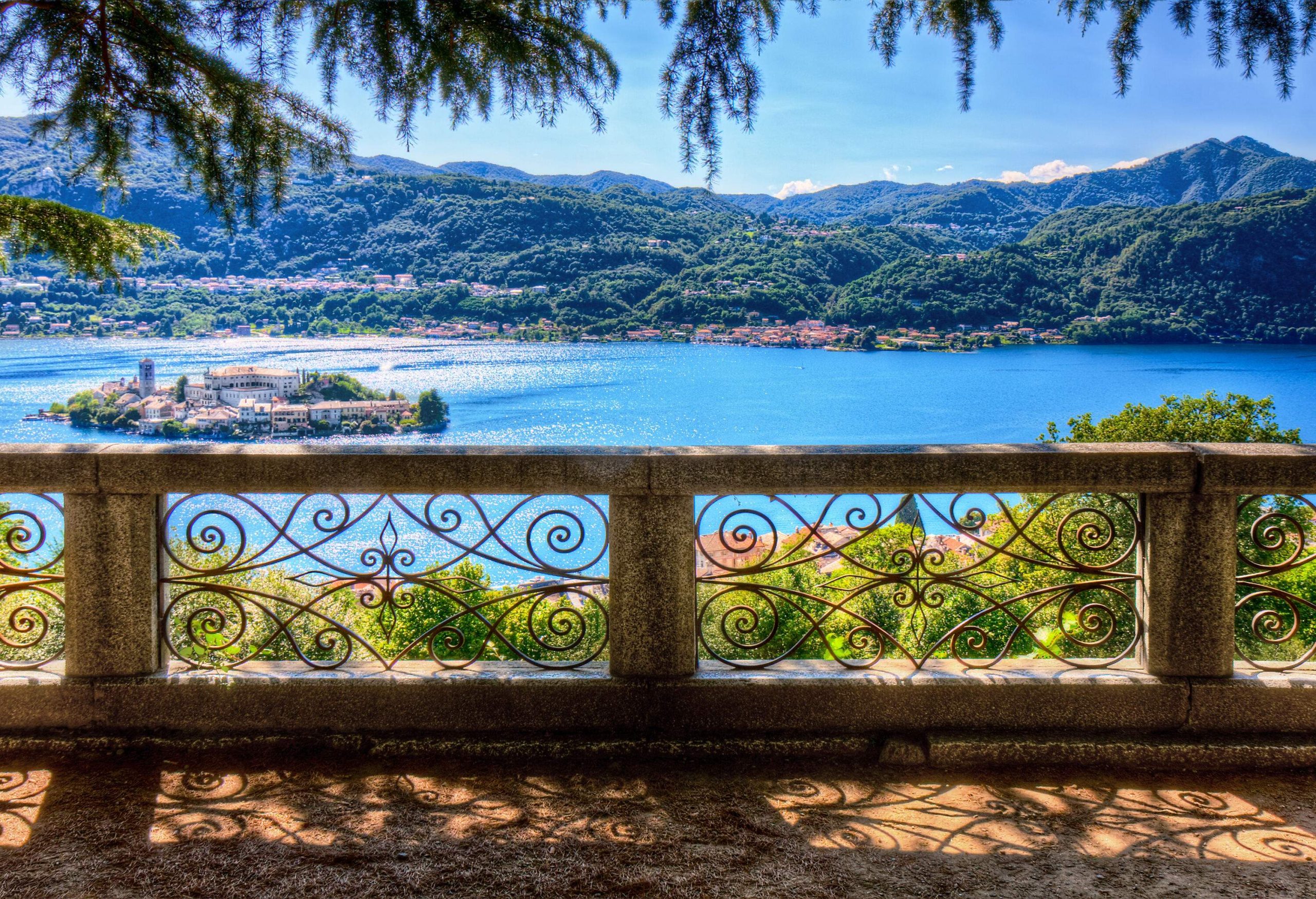 A concrete balcony with decorated railing overlooks an island settlement in the middle of the lake.