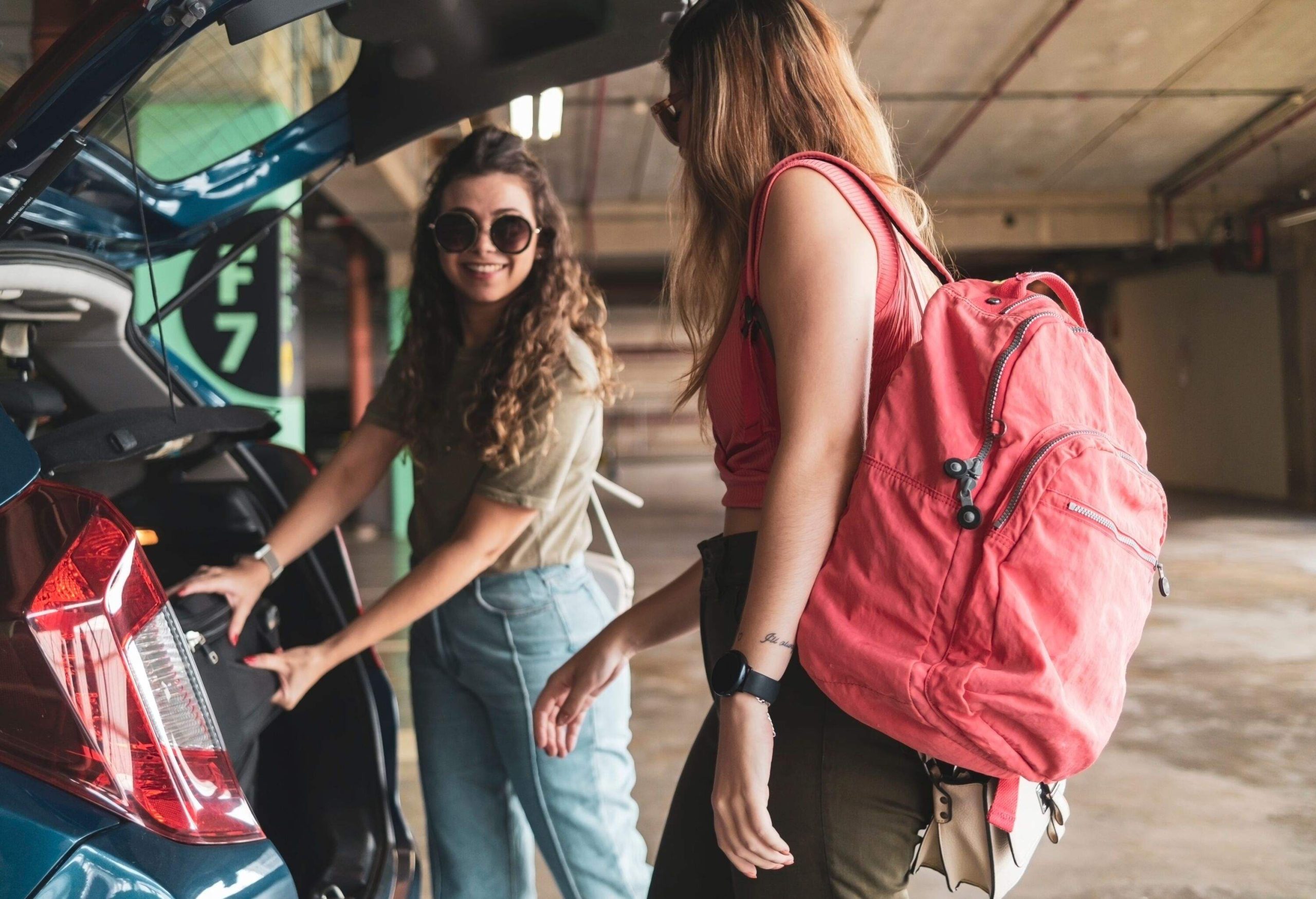 Photo of two friends in an airport. Young women...Taking the suitcases from the car.