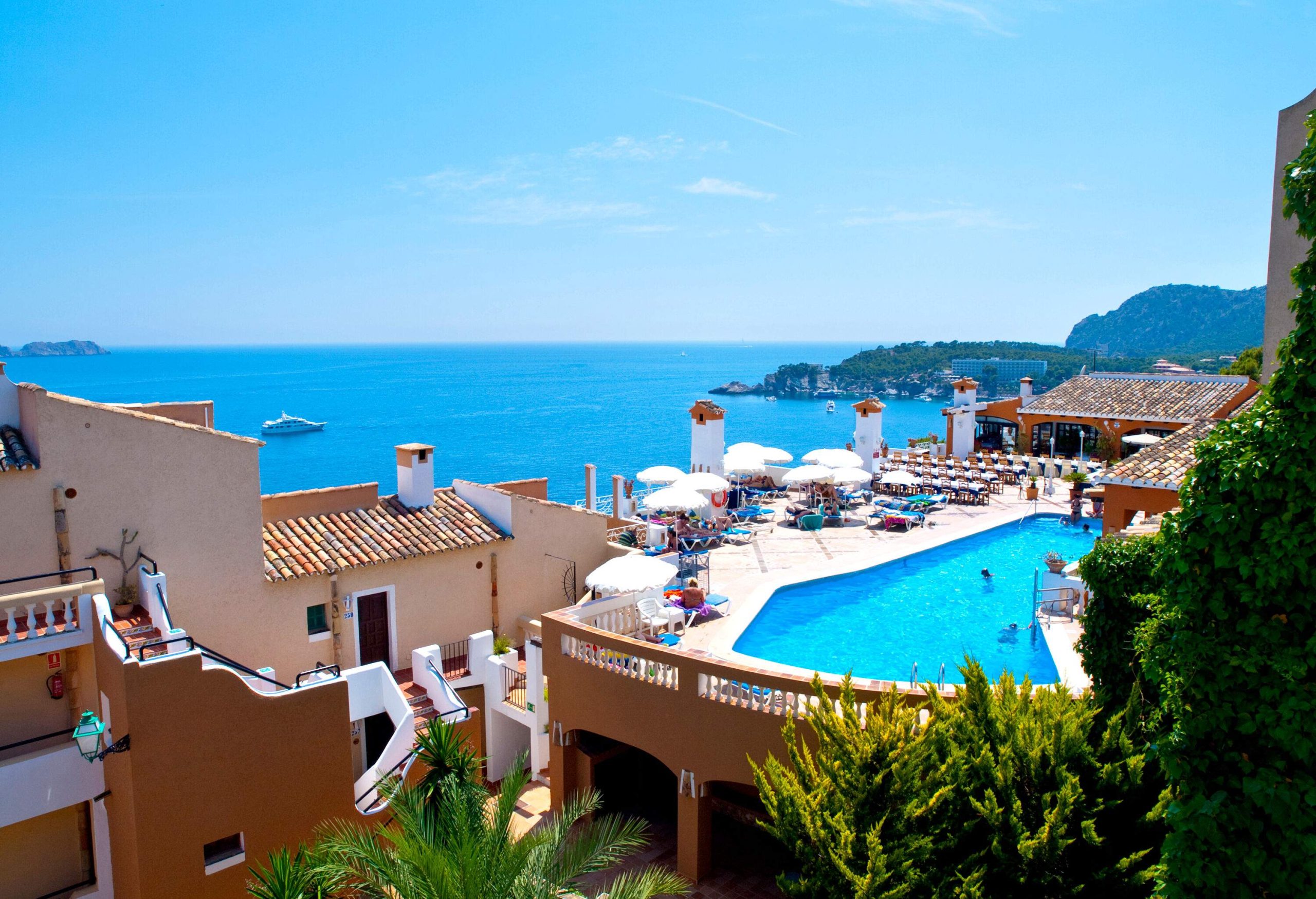 A traditional building with a rooftop pool overlooking the blue sea against the blue sky.