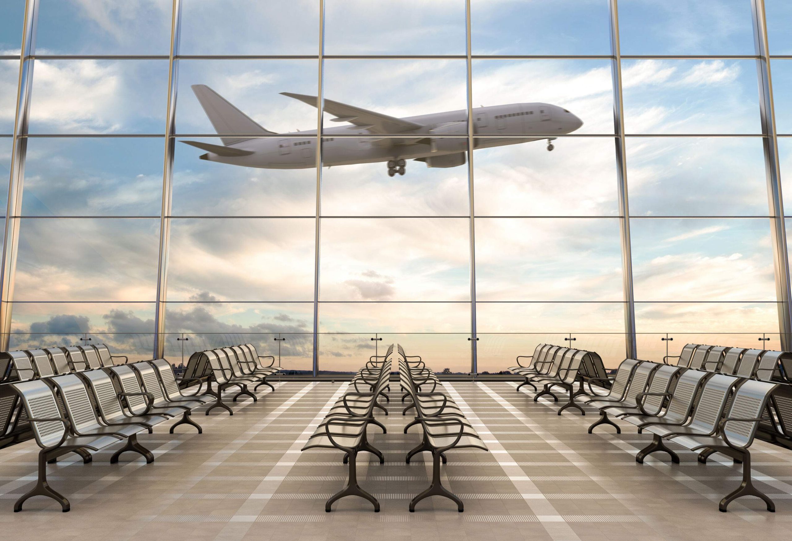 An airplane in flight passing by the large glass windows of the terminal.
