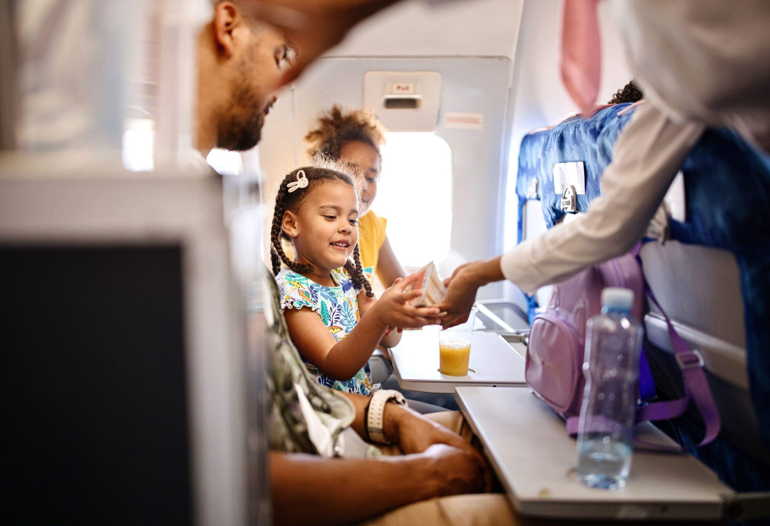 A little girl taking a snack handed by a cabin crew during flight.