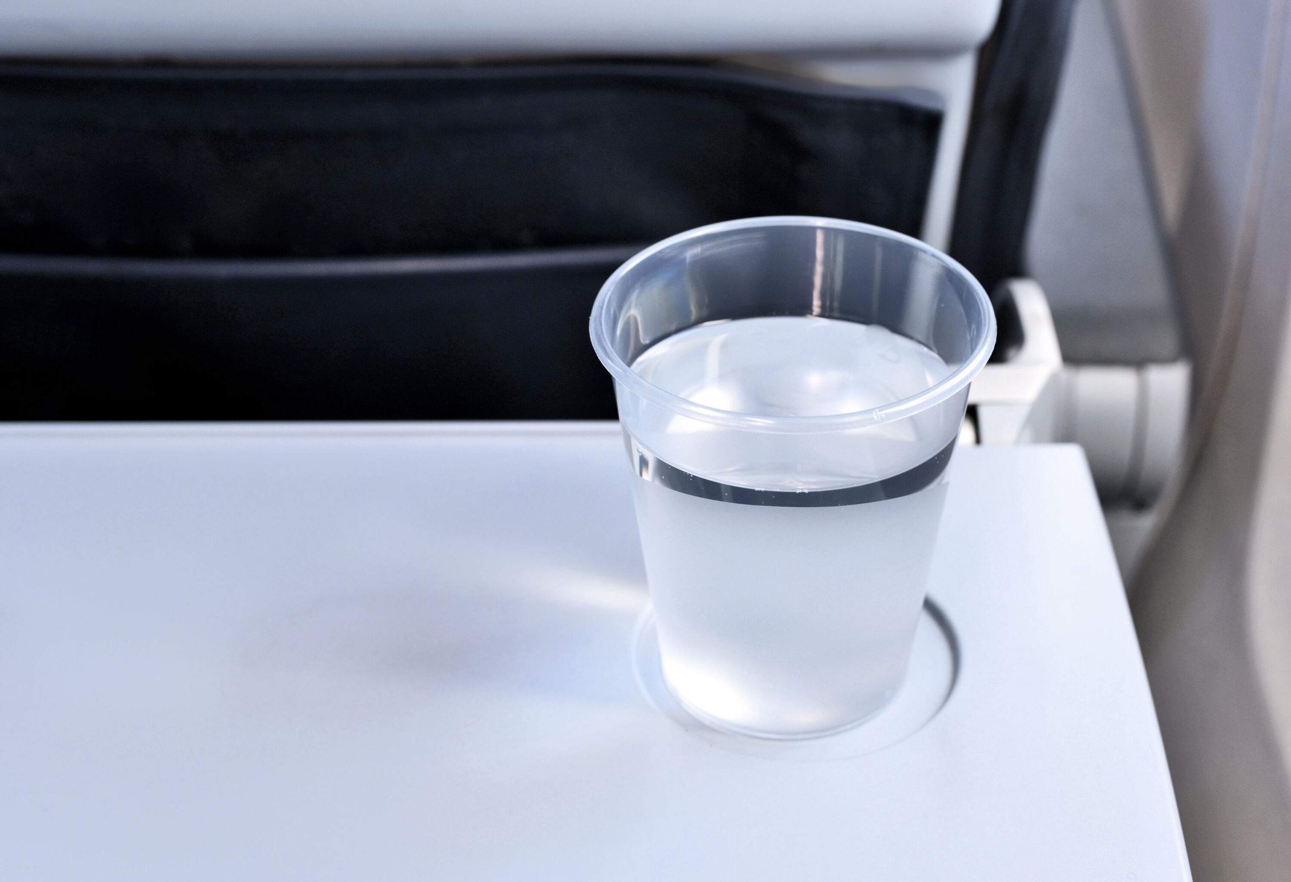 A plastic cup of water on a tray table.