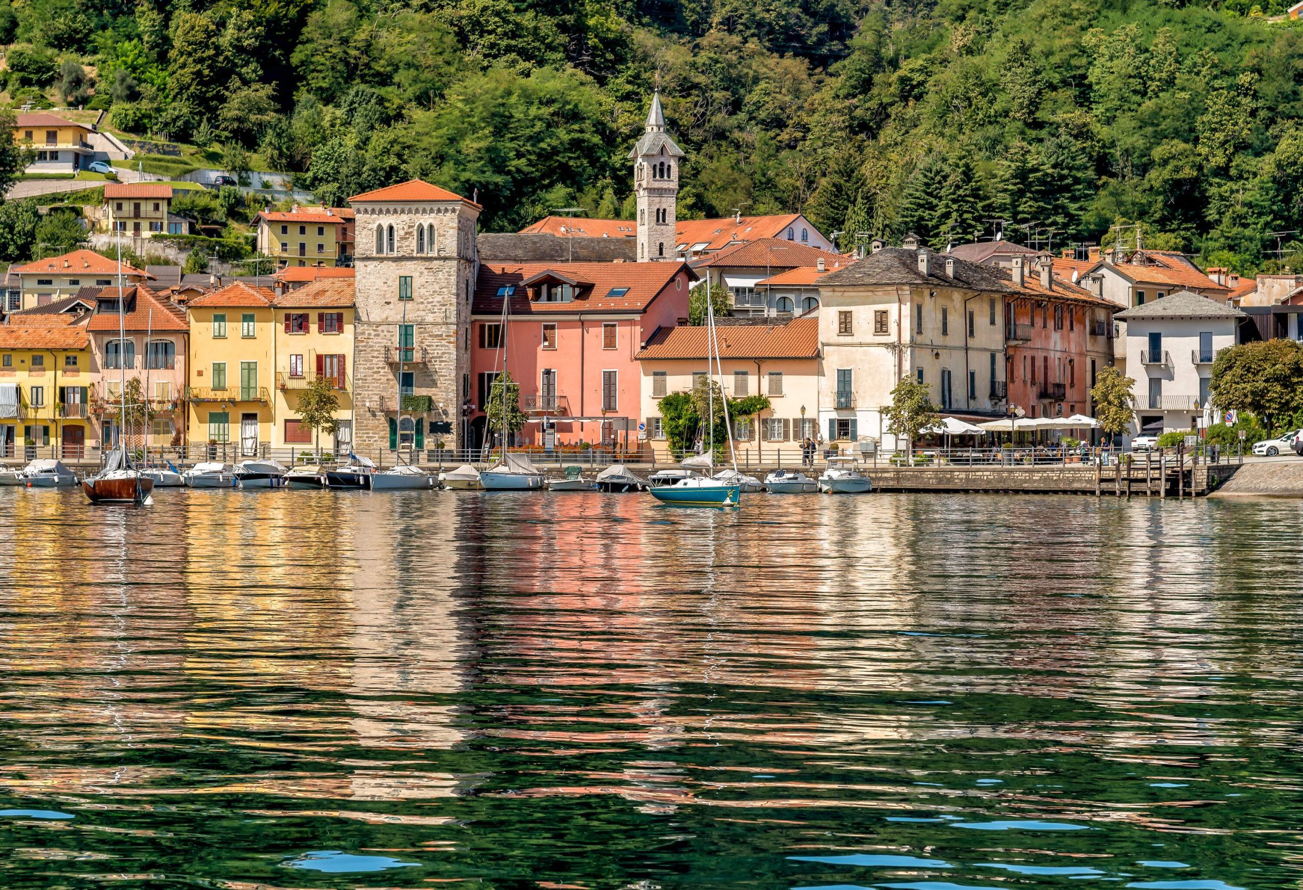 Colourful village houses beside a harbour lined with anchored boats.