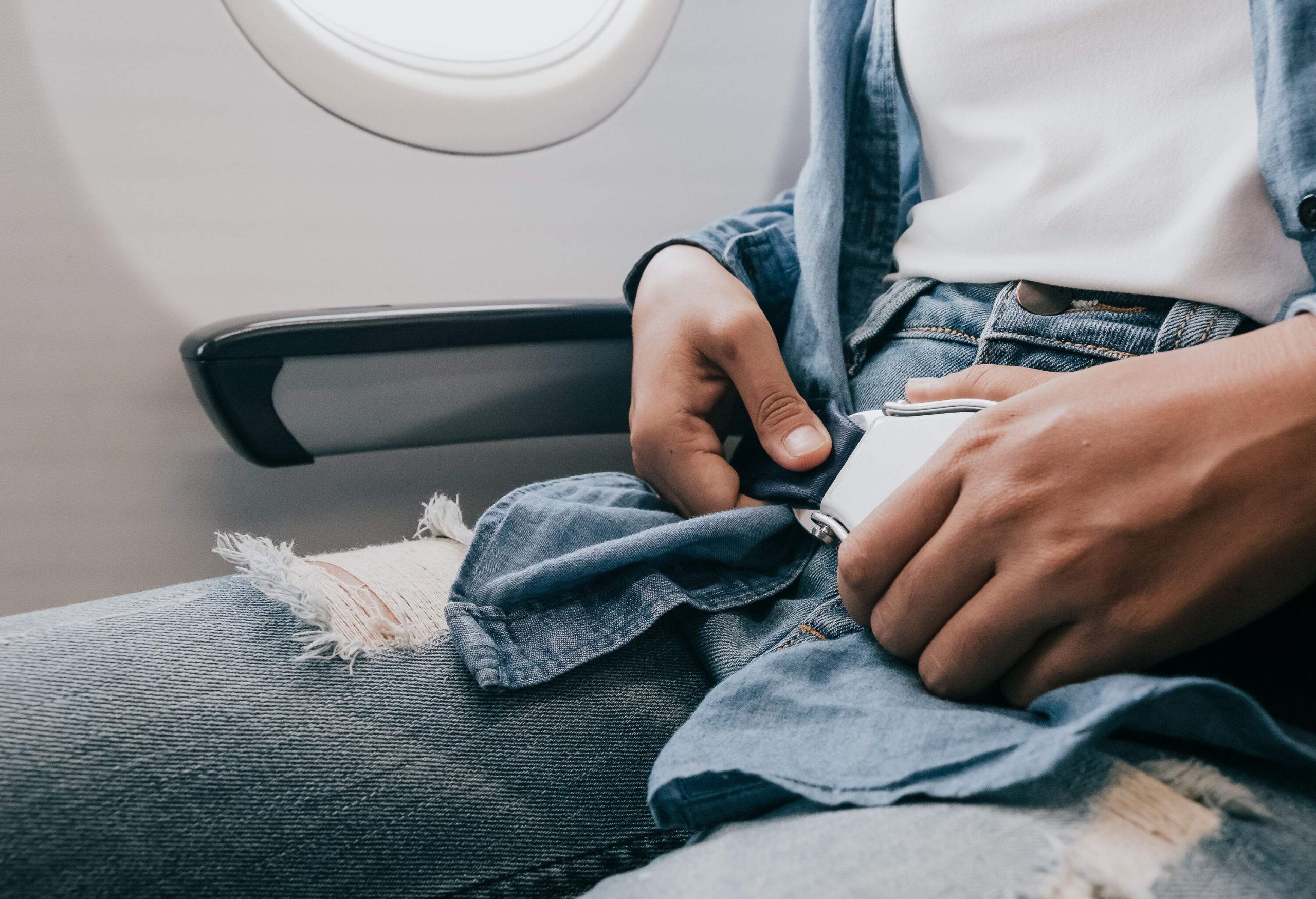 A man fastens his seatbelt while seated inside an airplane.