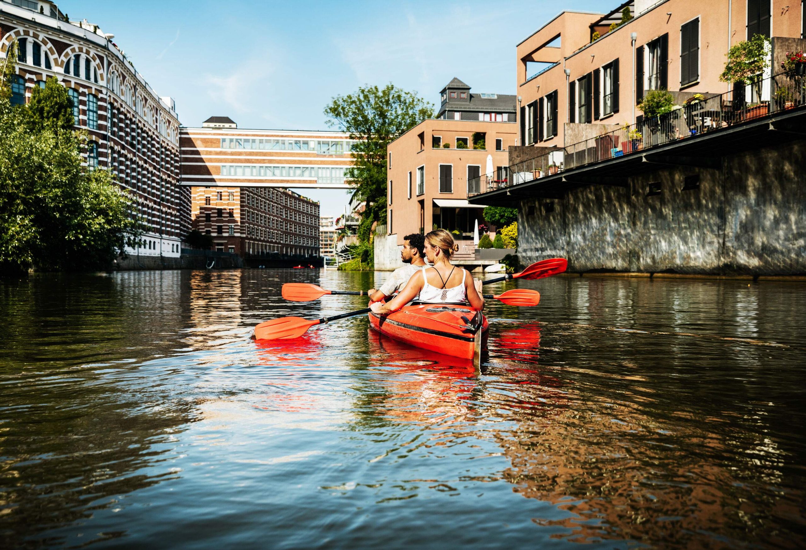 A couple in a kayak paddling on the tranquil canal flanked by classic buildings.