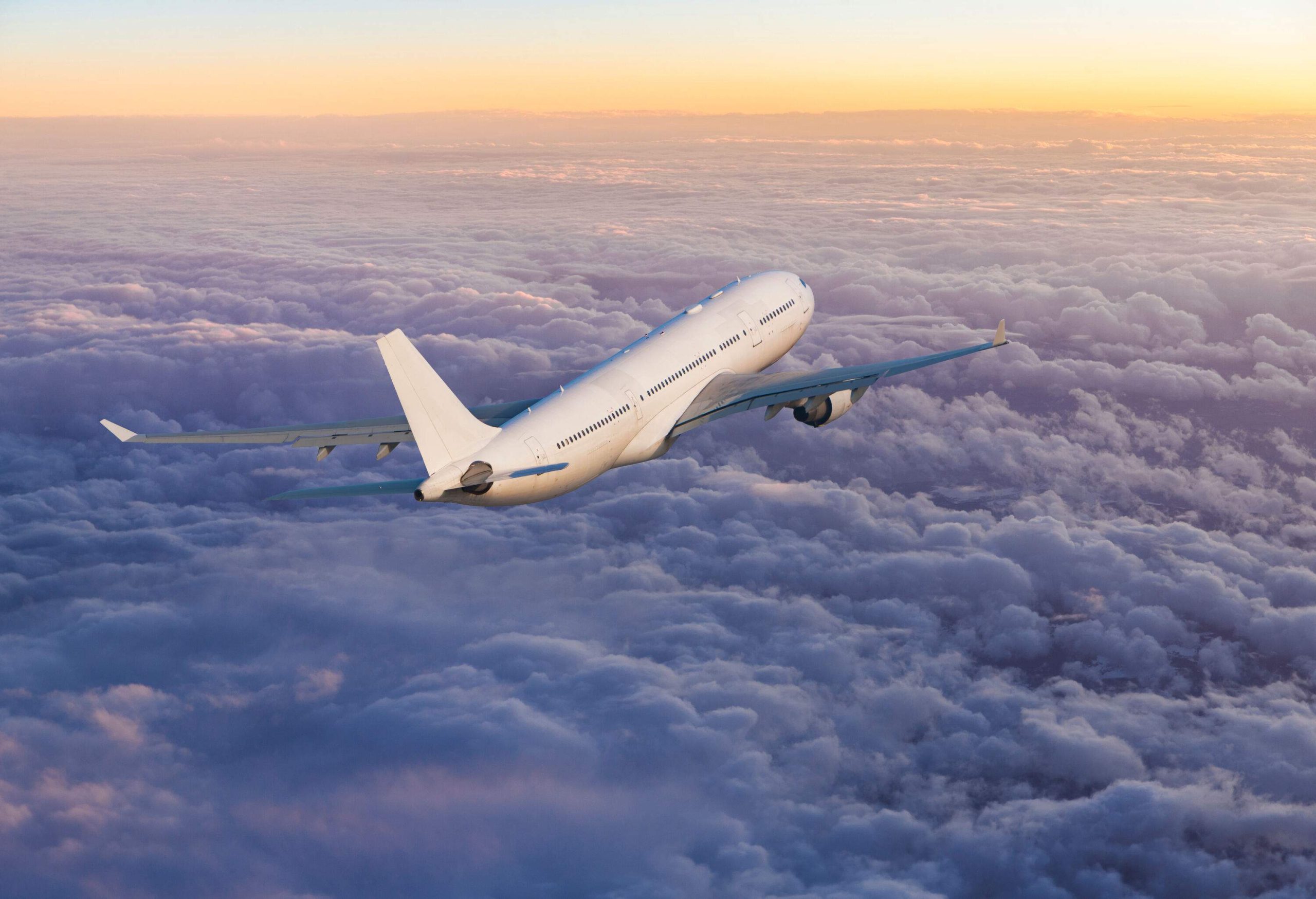 A passenger jet airplane gracefully glides above fluffy clouds.