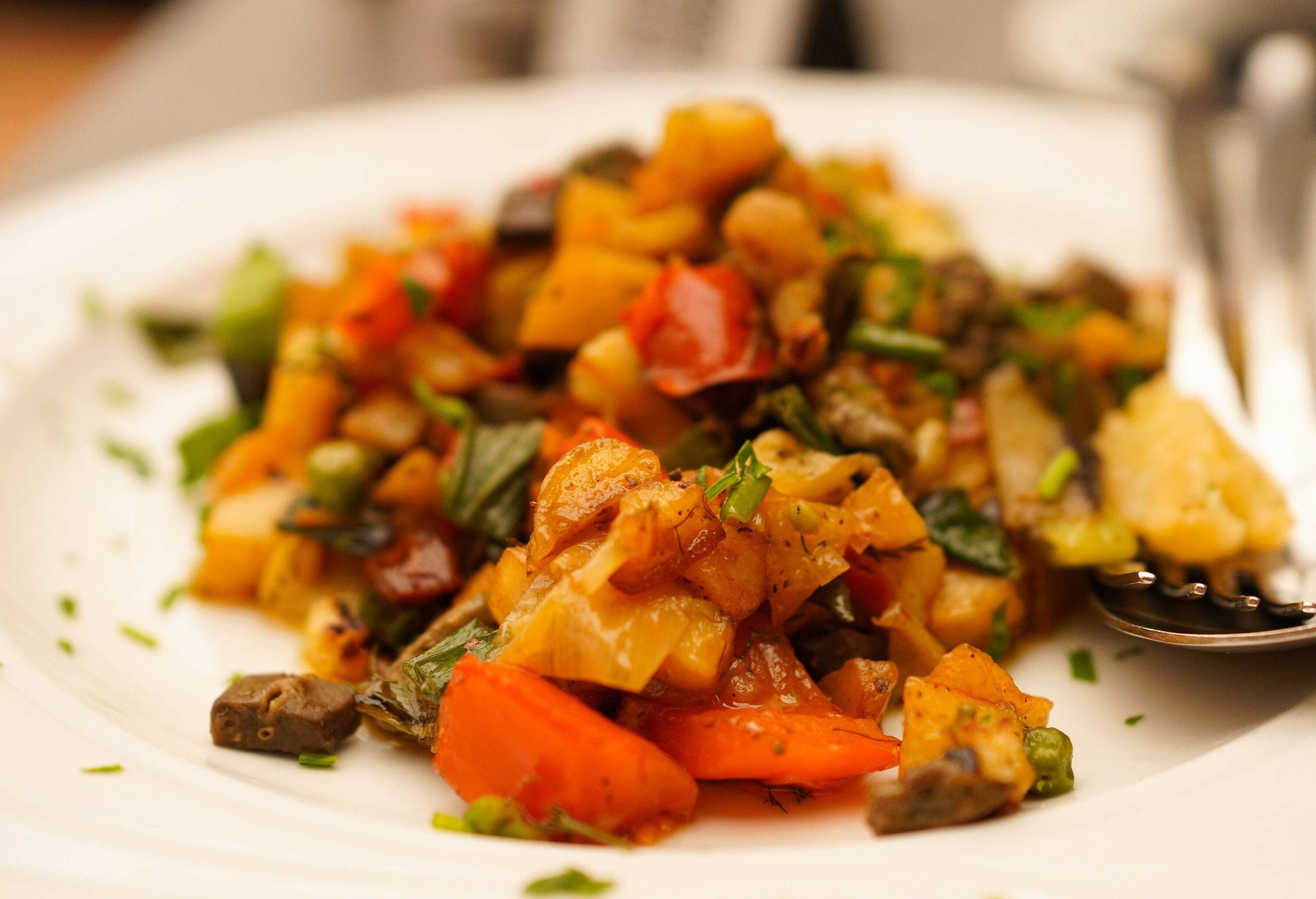 A stir-fried dish with potatoes, carrots, and green vegetables.