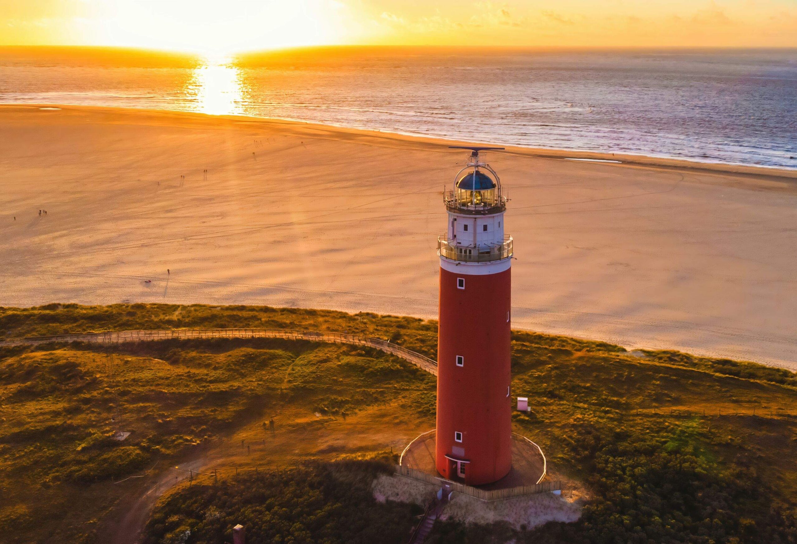 Texell lighthouse during sunset Netherlands Dutch Island Texel in summer with sand dunes at the Wadden Island. drone aerial view from above during sunset at the beach with a sunset in the ocean