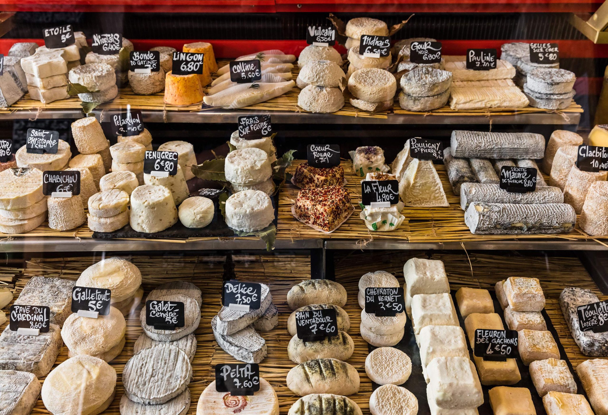 A display of assorted cheese with individual labels and pricing.