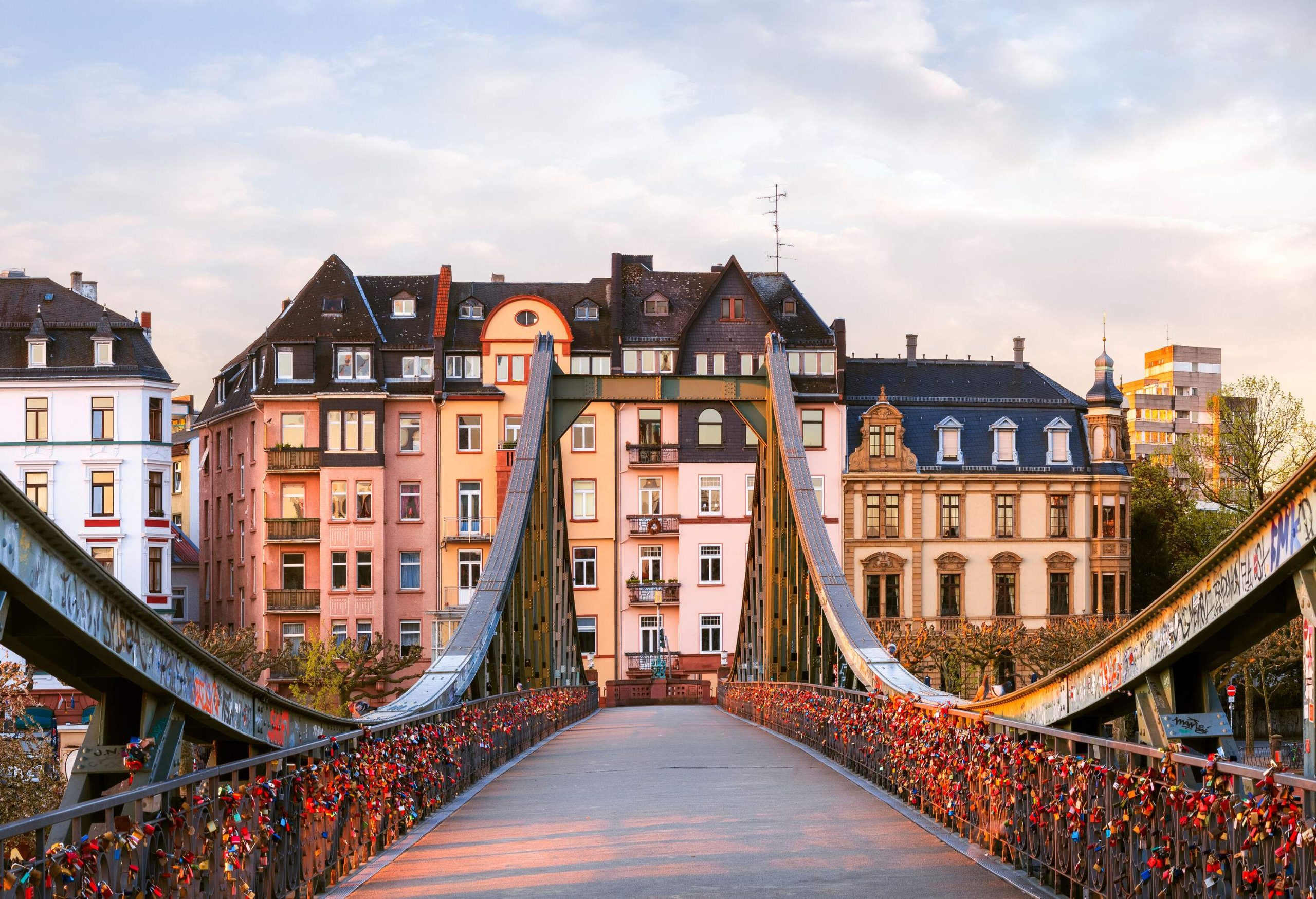 A footbridge with colourful locks on either side of the rails.